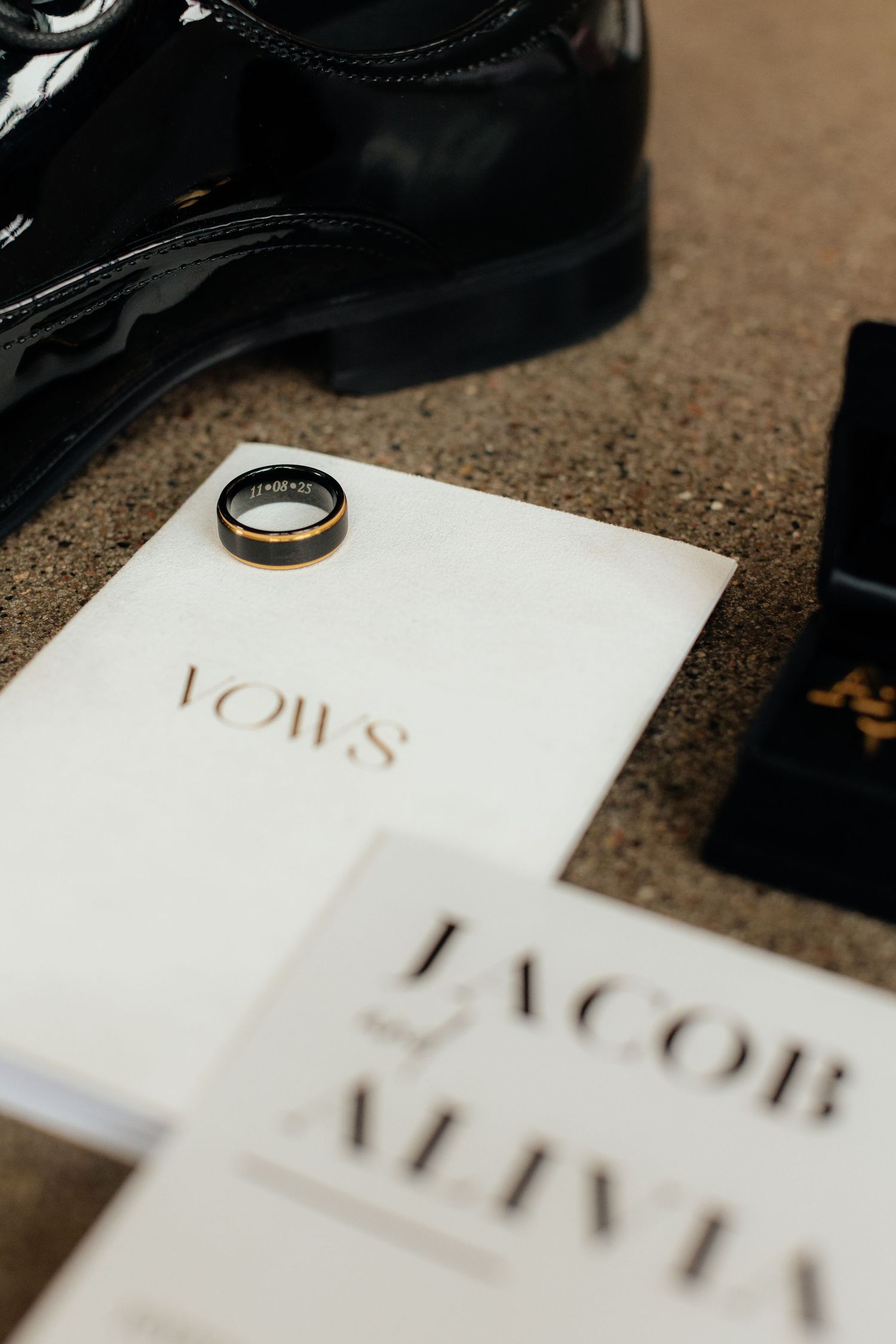 Close-up of wedding invitation with gold text and rings.