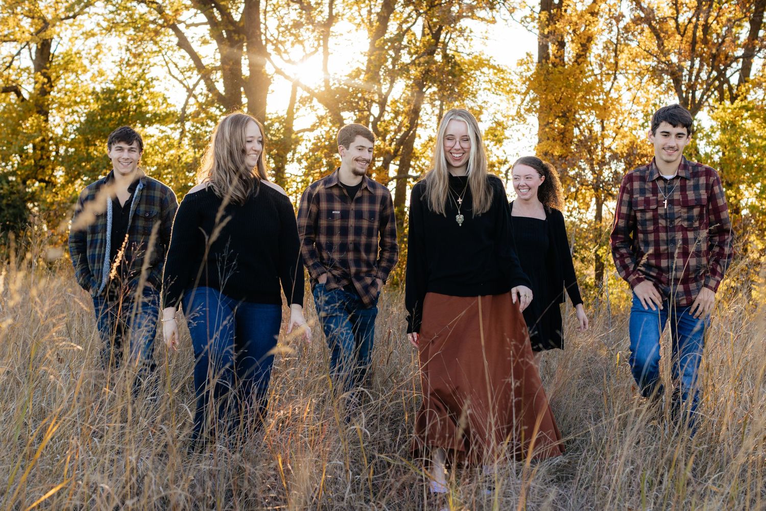 Family group photo taken at sunset in a field with golden autumn light.