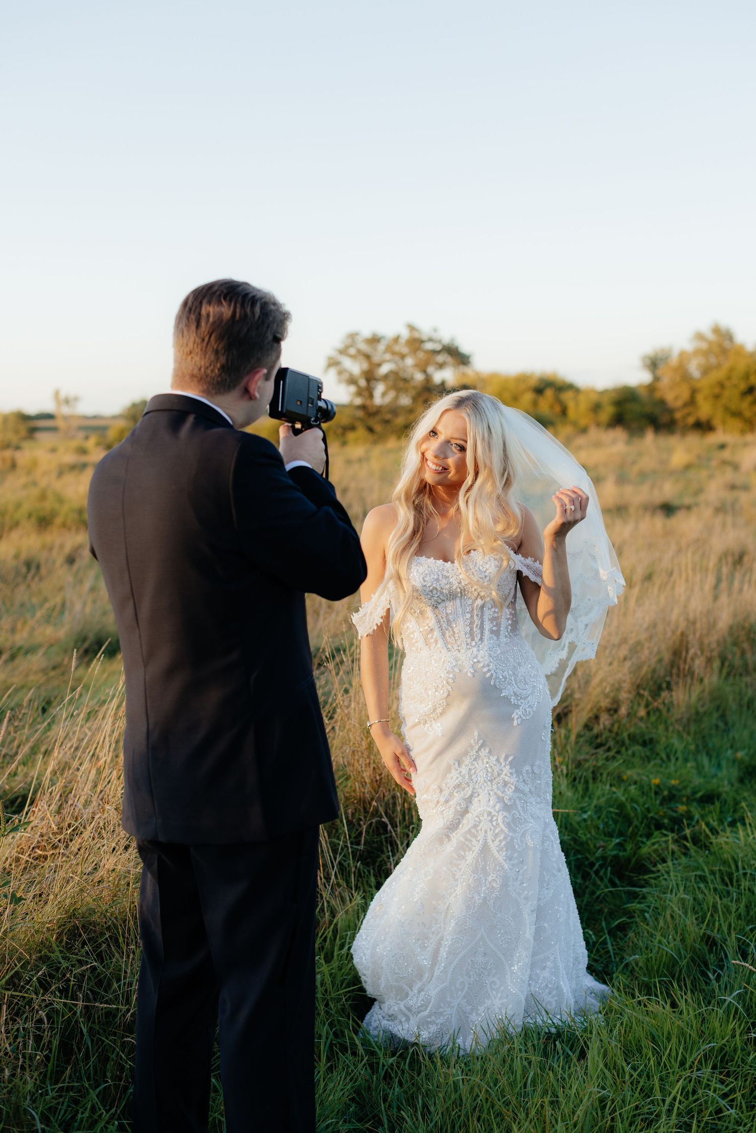 Wedding photography session in a sunlit meadow with tall grass.