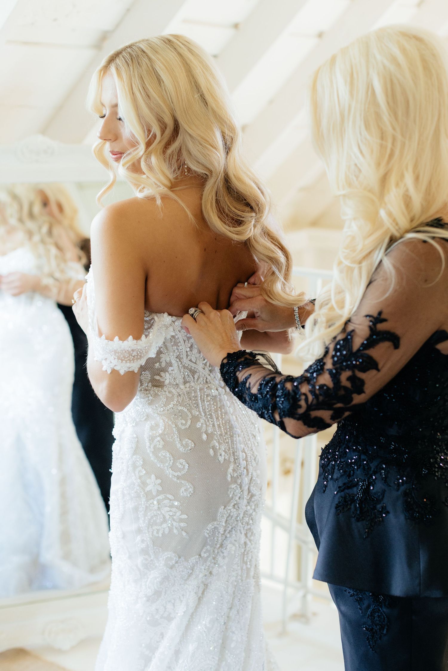 Close-up details of intricate lace and beadwork on a white wedding gown being fitted.