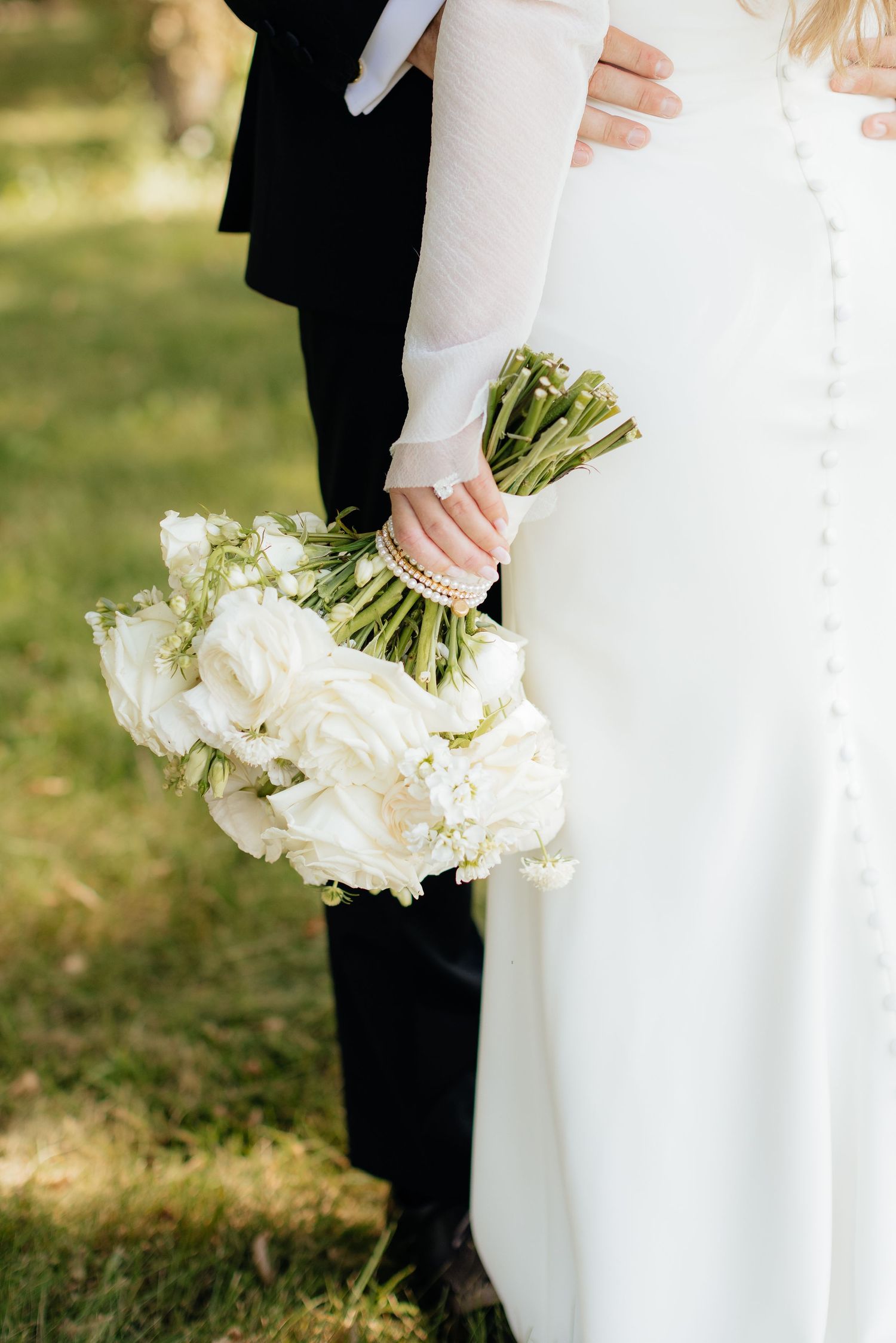 Close-up of white wedding bouquet against bride's elegant dress.