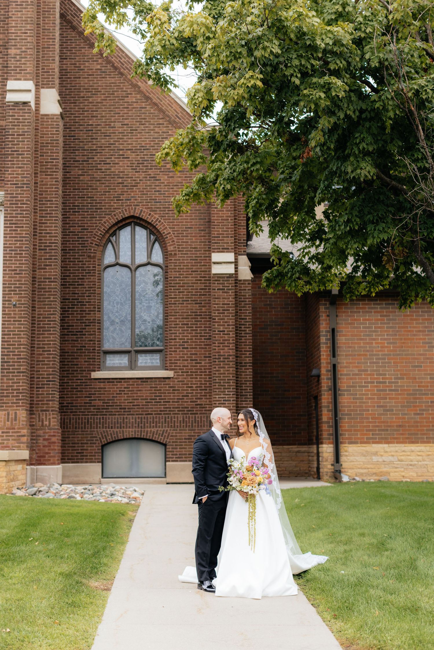 Elegant brick church exterior with landscaped lawn on a sunny wedding day.