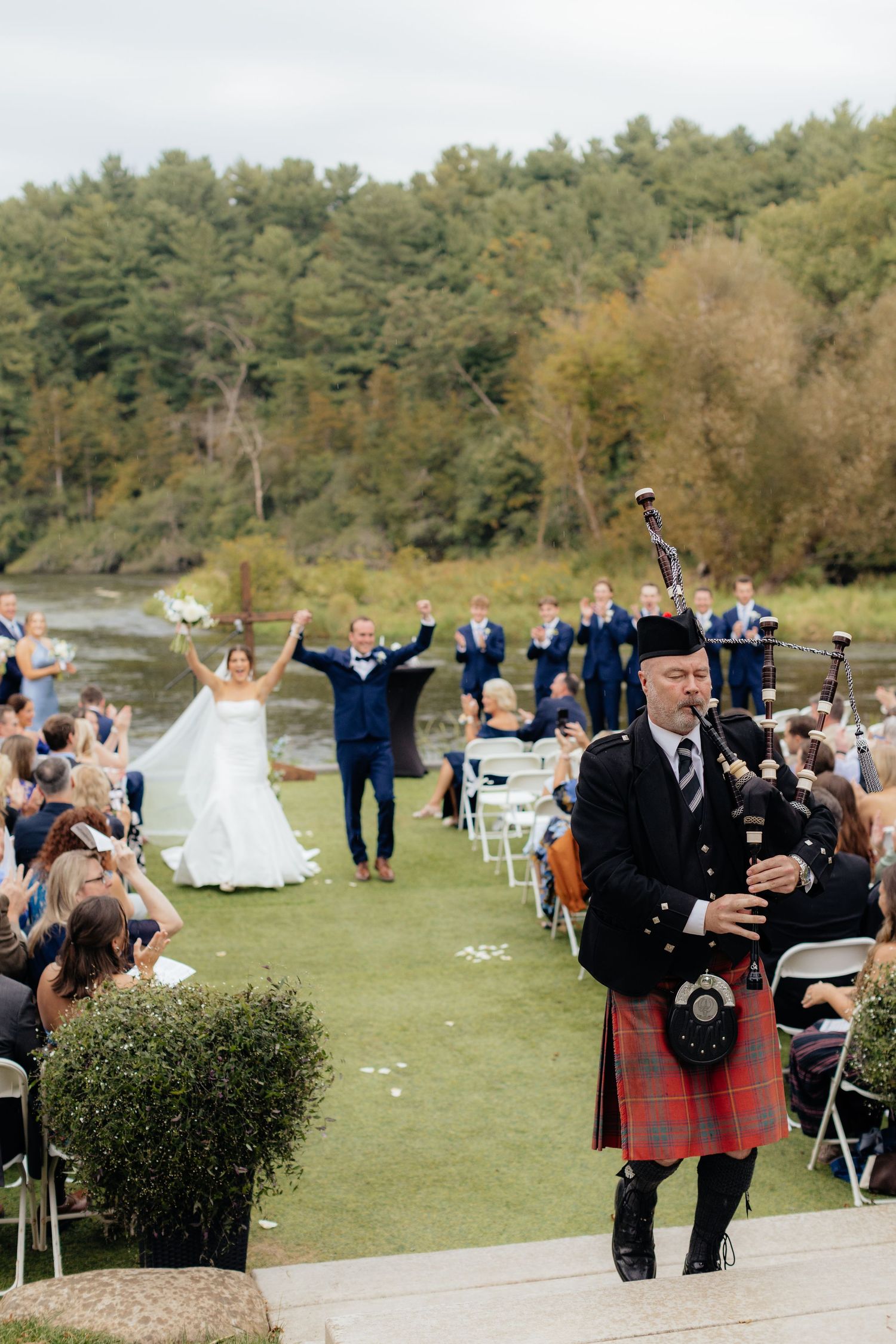 Scottish wedding ceremony with guests and traditional kilts in an outdoor setting.