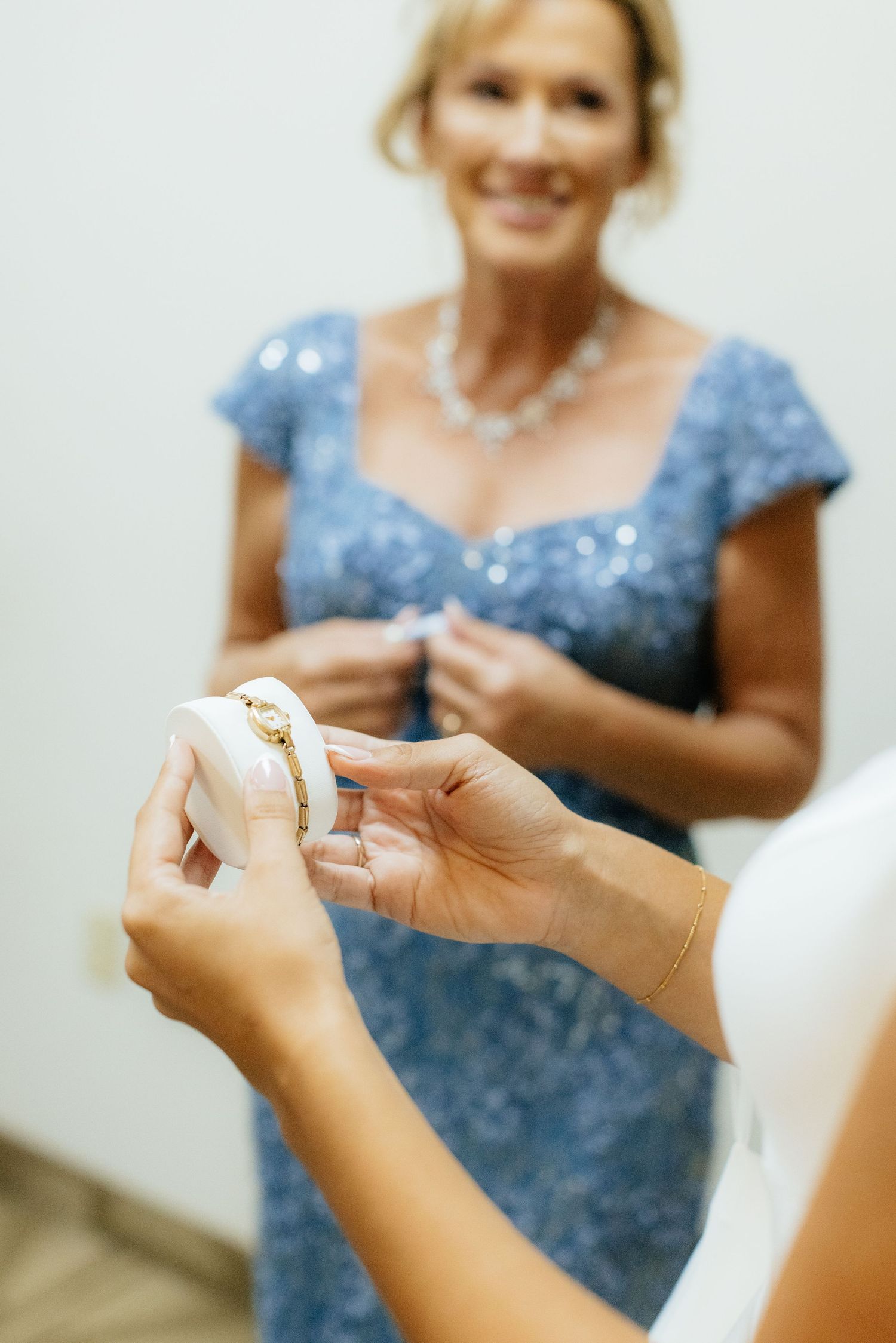 Close-up of hands exchanging jewelry during wedding preparations.
