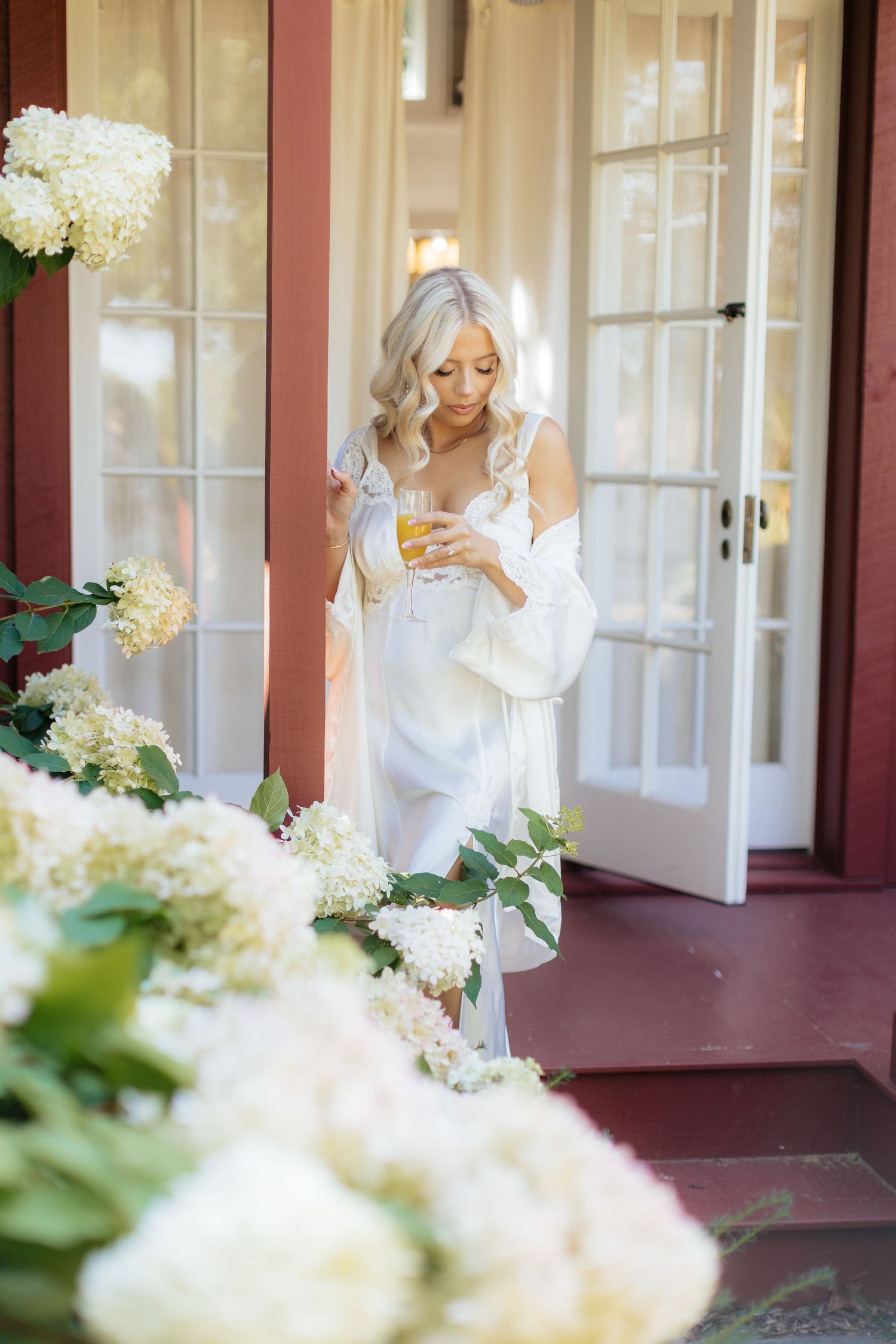 Sunlit porch with white hydrangea blooms and classic French doors.