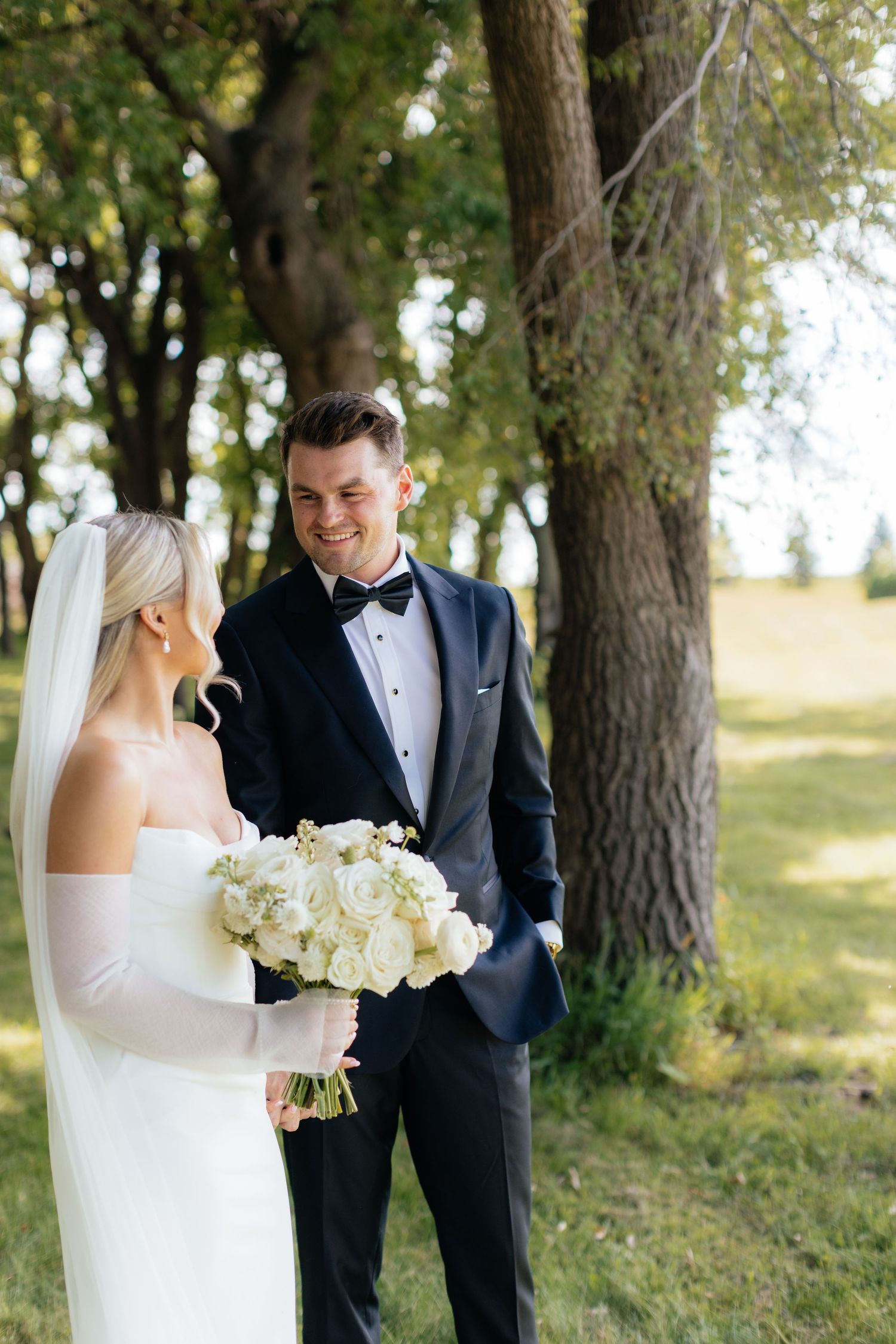 Elegant wedding photo session in a wooded area with white floral bouquet.