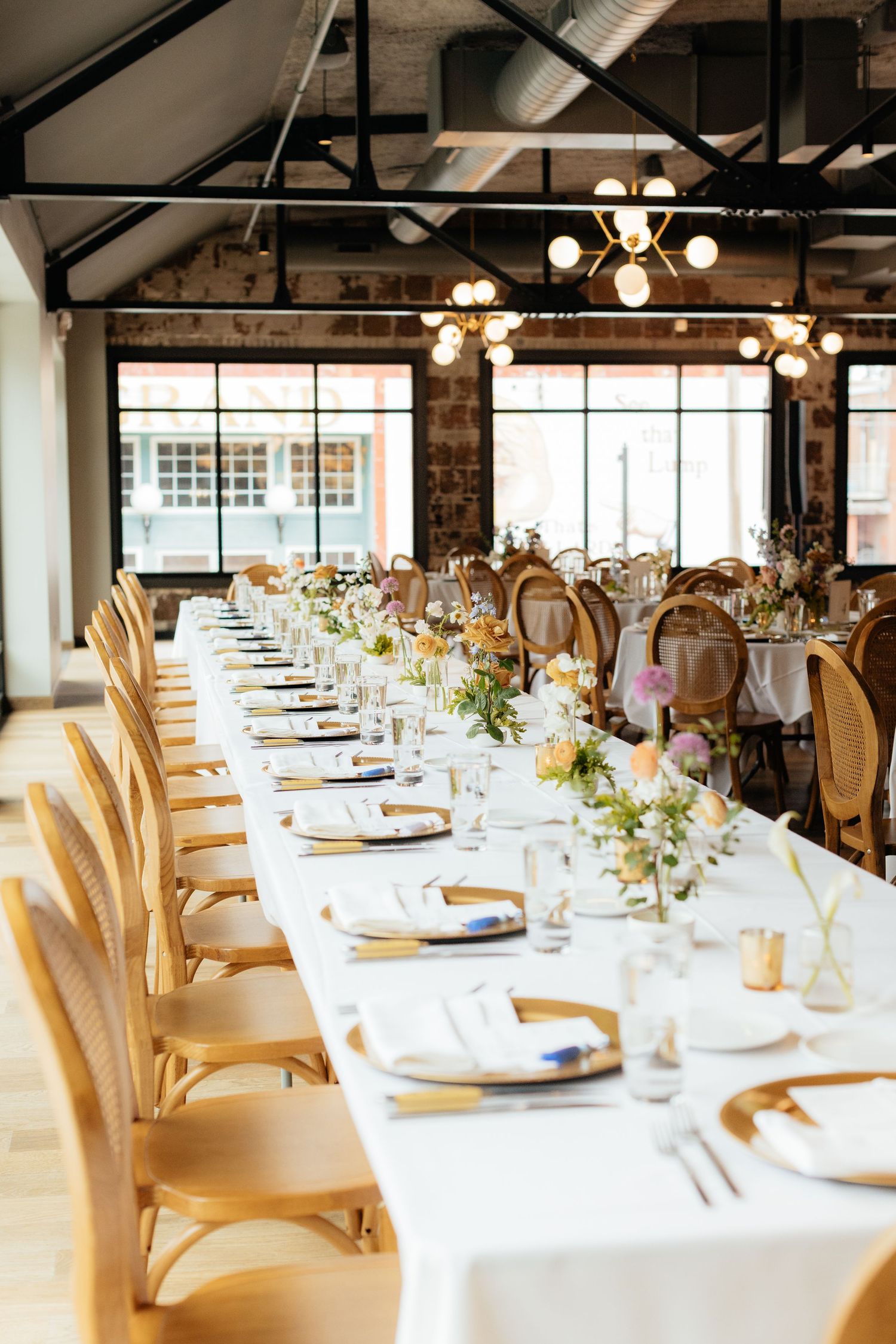 Wedding reception venue with elegant table settings and cream-colored chairs.