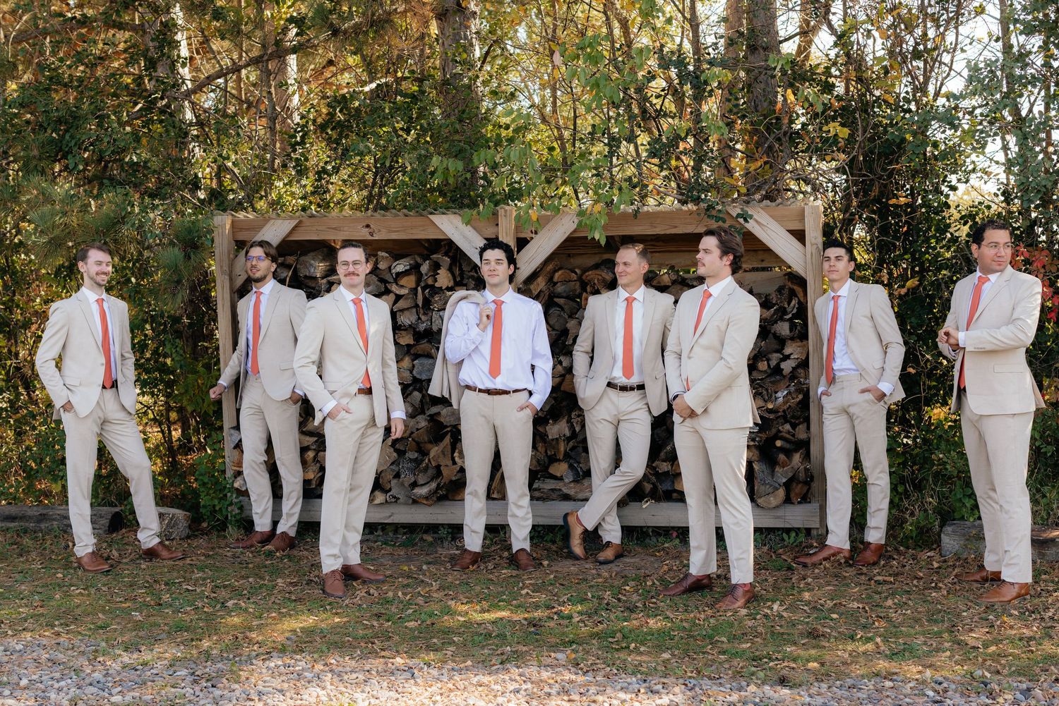 Groomsmen in light colored suits lined up for formal wedding photo outdoors.