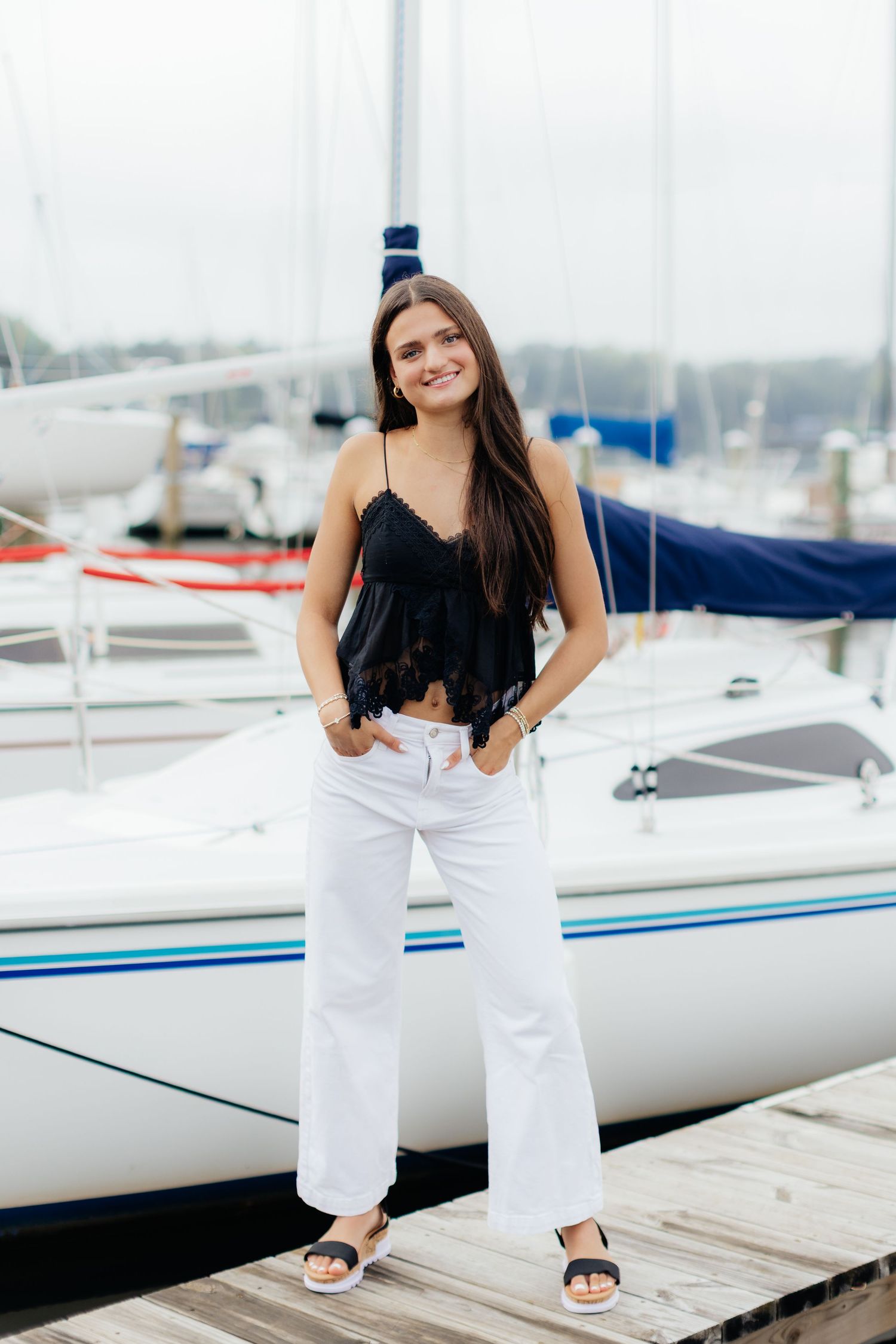 Casual marina photoshoot with sailboats in background.