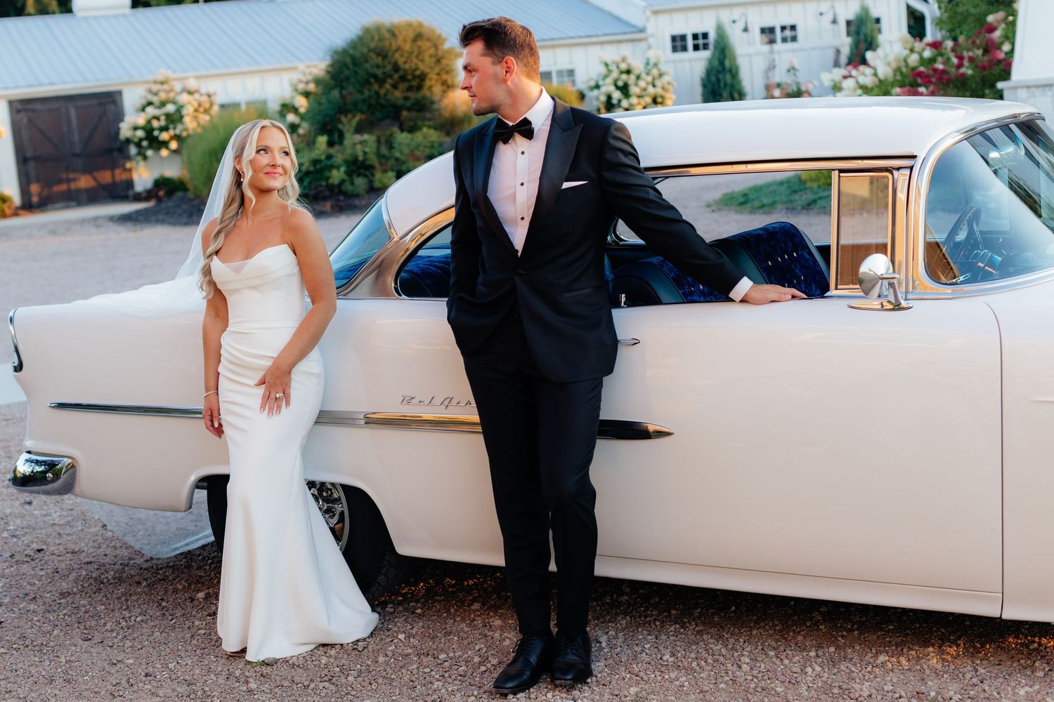 Classic white vintage car parked outside with a wedding couple.