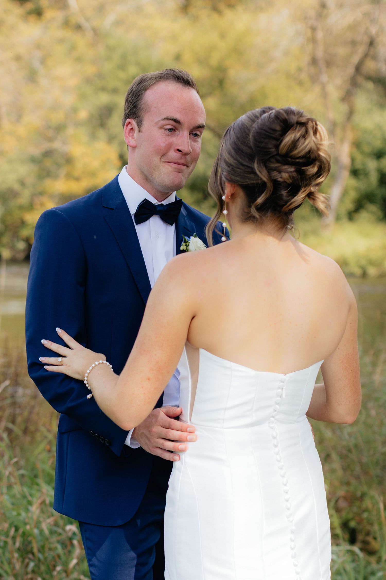 A romantic first look moment between newlyweds in a natural outdoor setting.