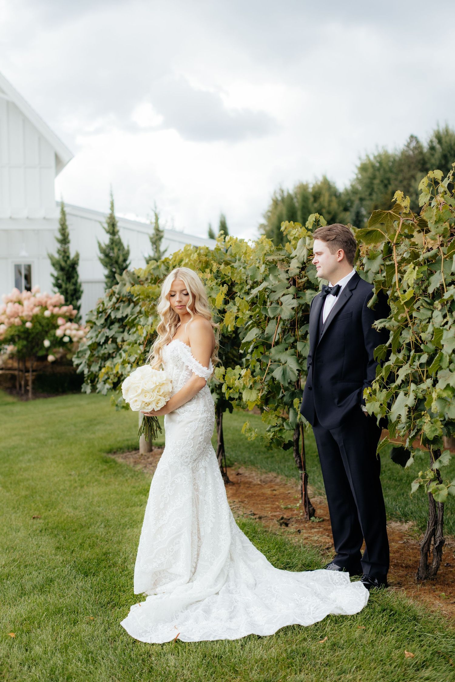 Elegant wedding photos taken in a vineyard with white chapel in background.