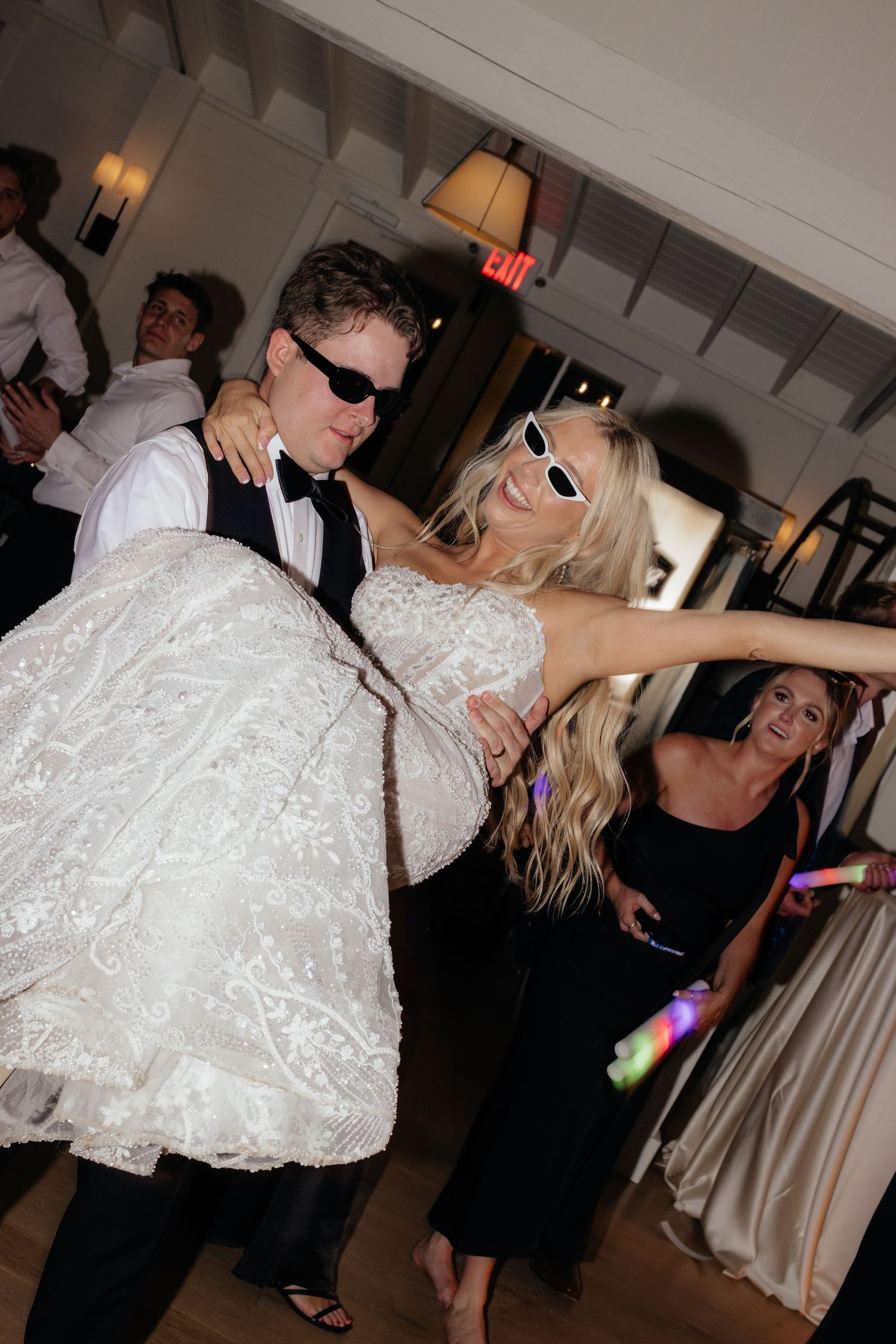 Wedding reception dance floor with guests celebrating under party lights.