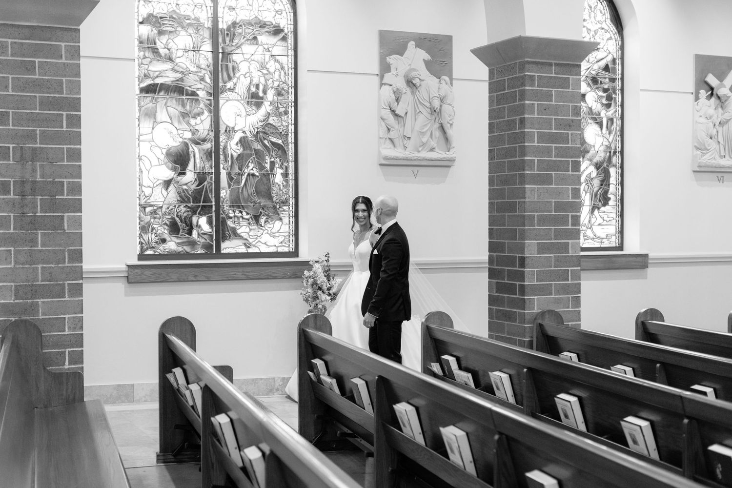 Black and white photo showing a church interior with wooden pews and brick columns.