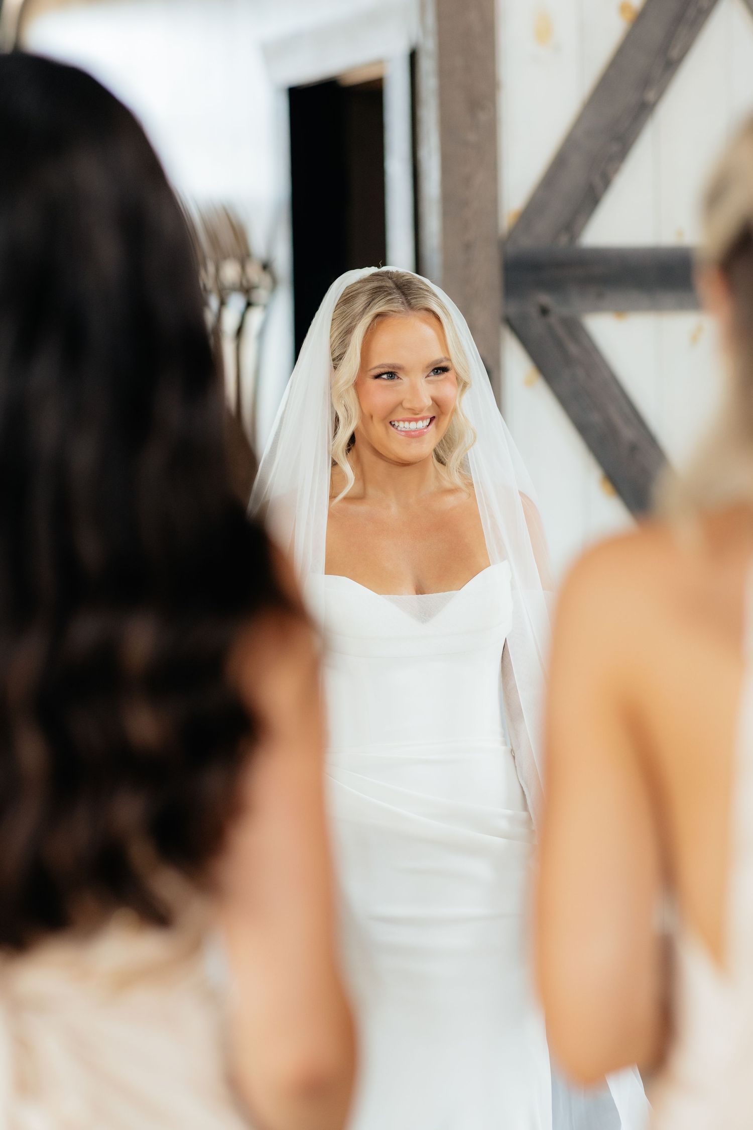 Wedding day preparations with bride looking in mirror at modern venue.