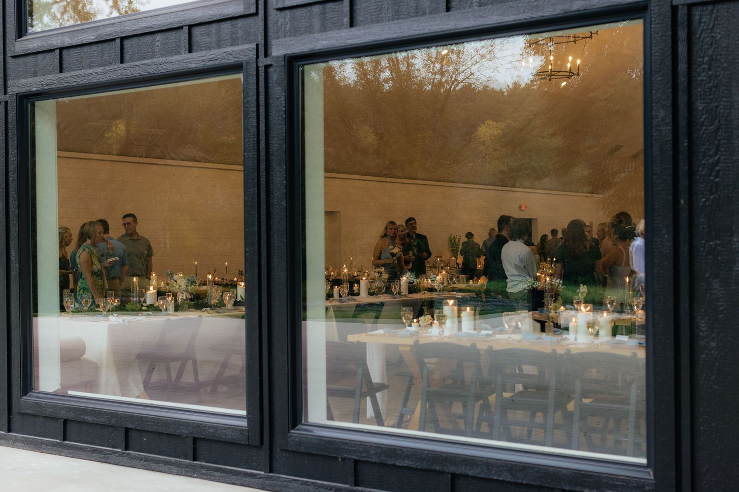 Modern venue's exterior windows reflecting the evening reception setup inside.