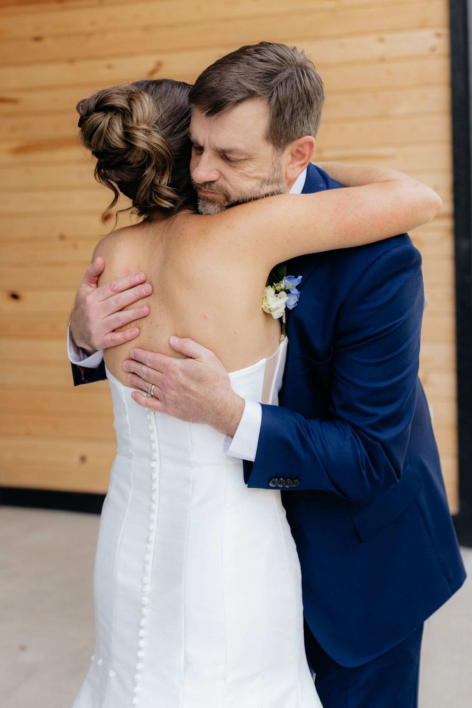 A couple shares an intimate embrace, with the groom in navy and bride in white.