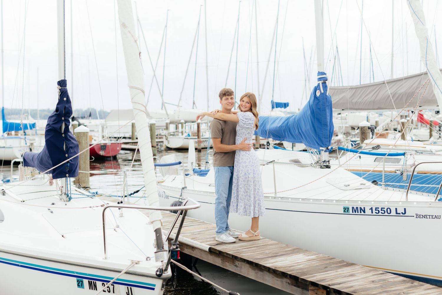 Sailboats docked at a marina with white sails and blue water on a sunny day.
