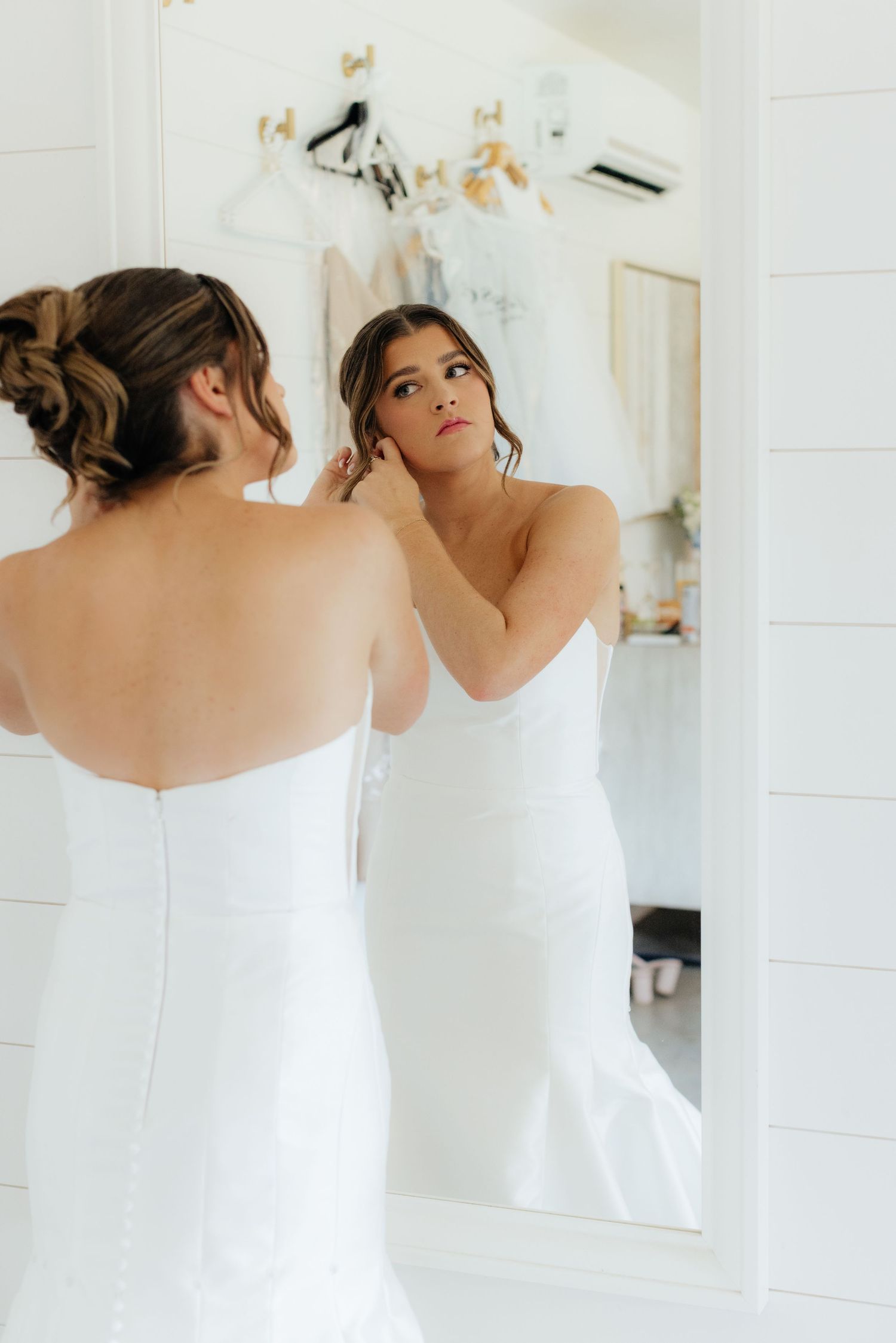 Elegant bridal portrait reflected in mirror showing back detail of fitted white wedding gown.