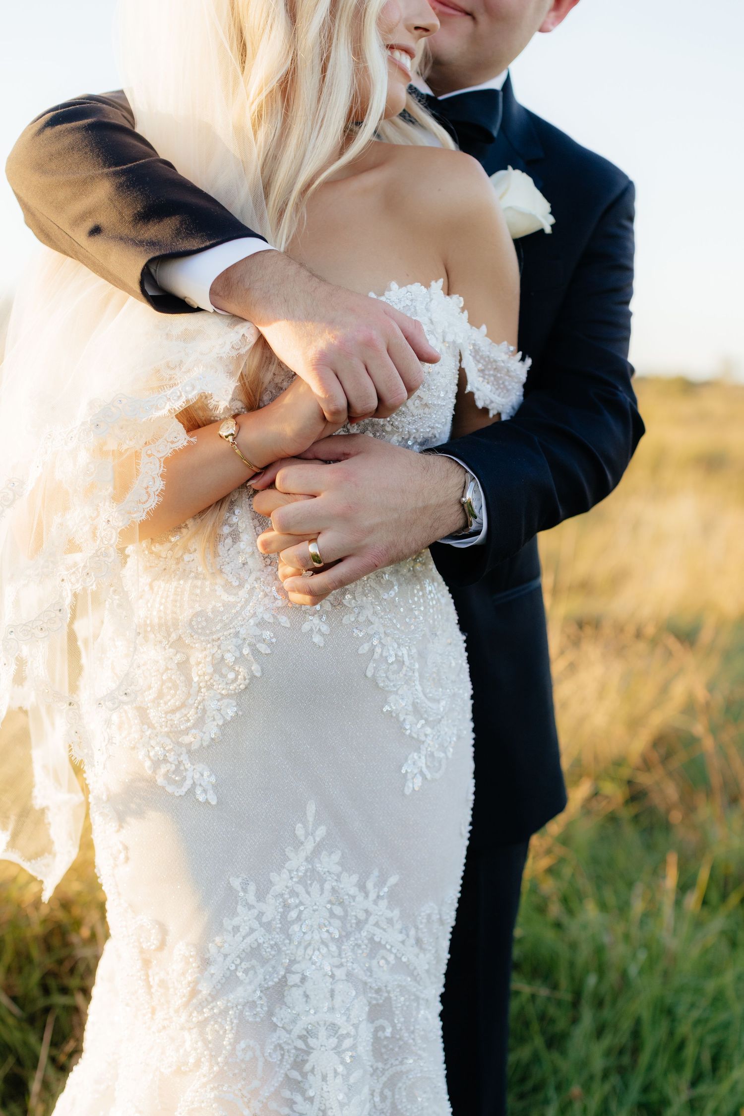 Detail shot of intricate lace wedding dress in natural outdoor lighting.