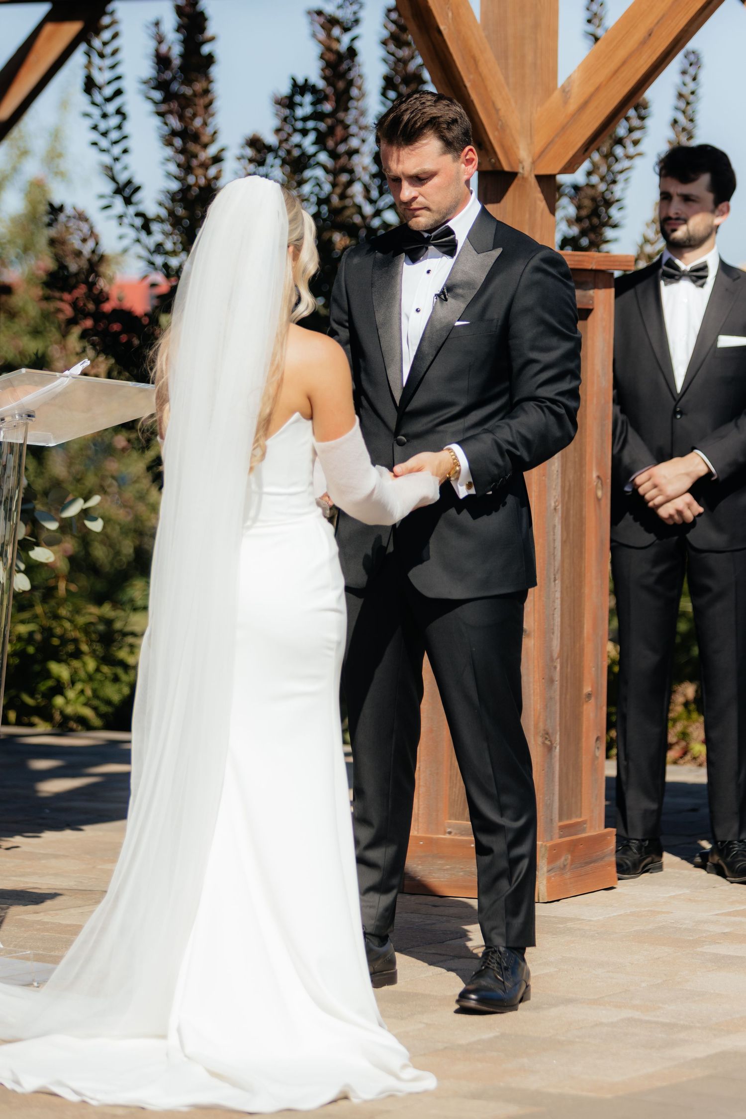 Elegant outdoor wedding ceremony under a wooden pergola structure.