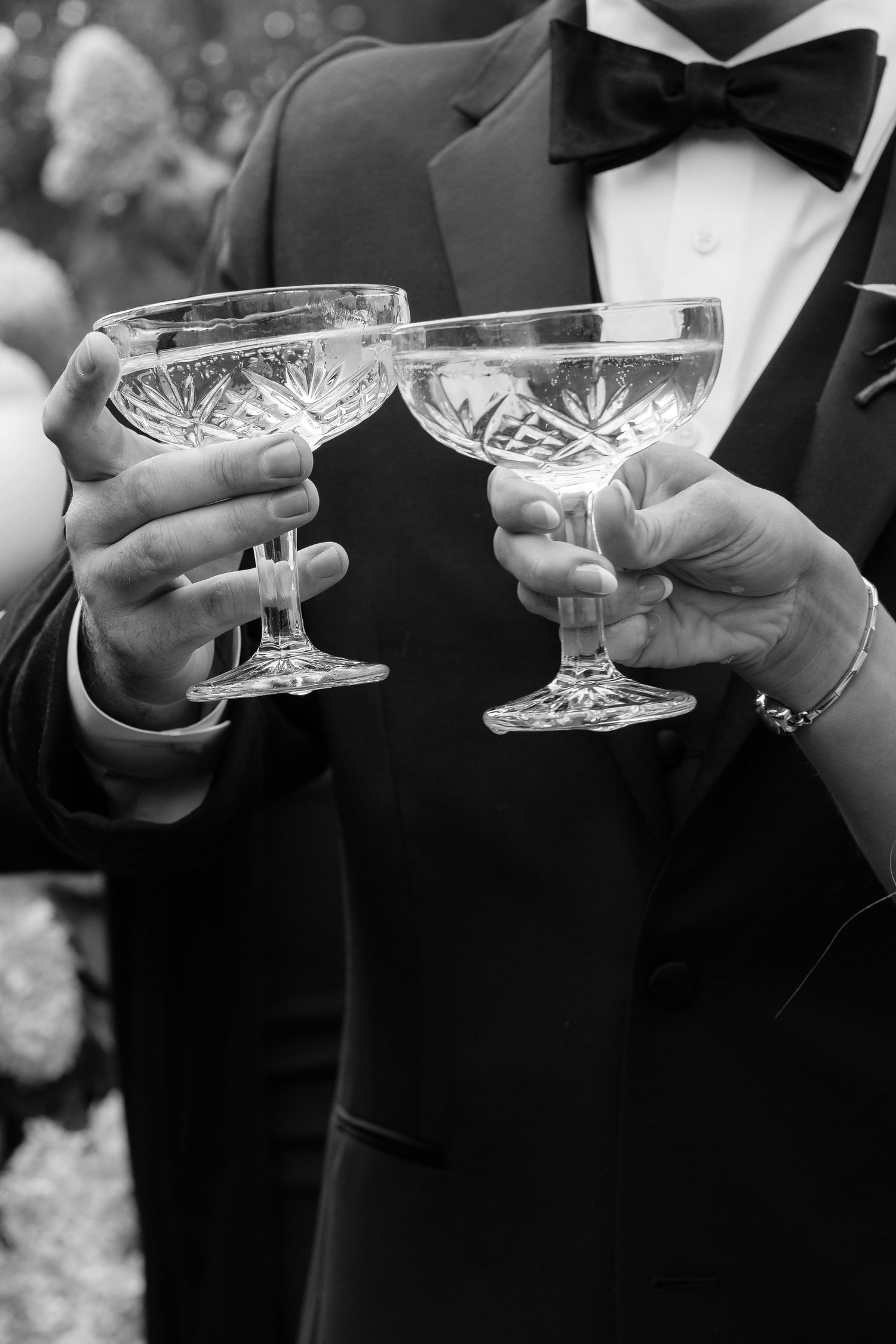 Crystal champagne coupes being held during a wedding toast celebration.
