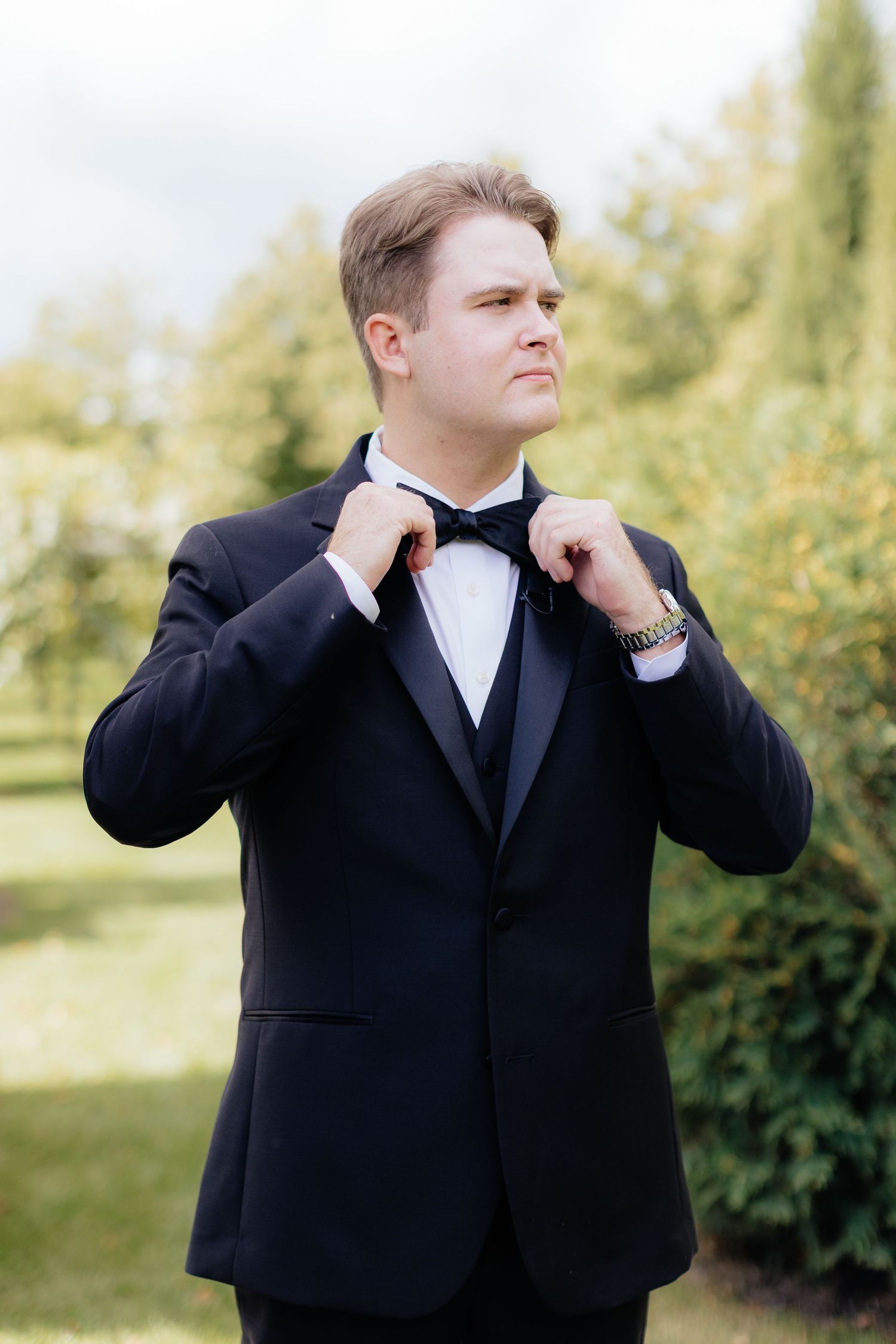 Classic black tuxedo with bowtie photographed in an outdoor garden setting.