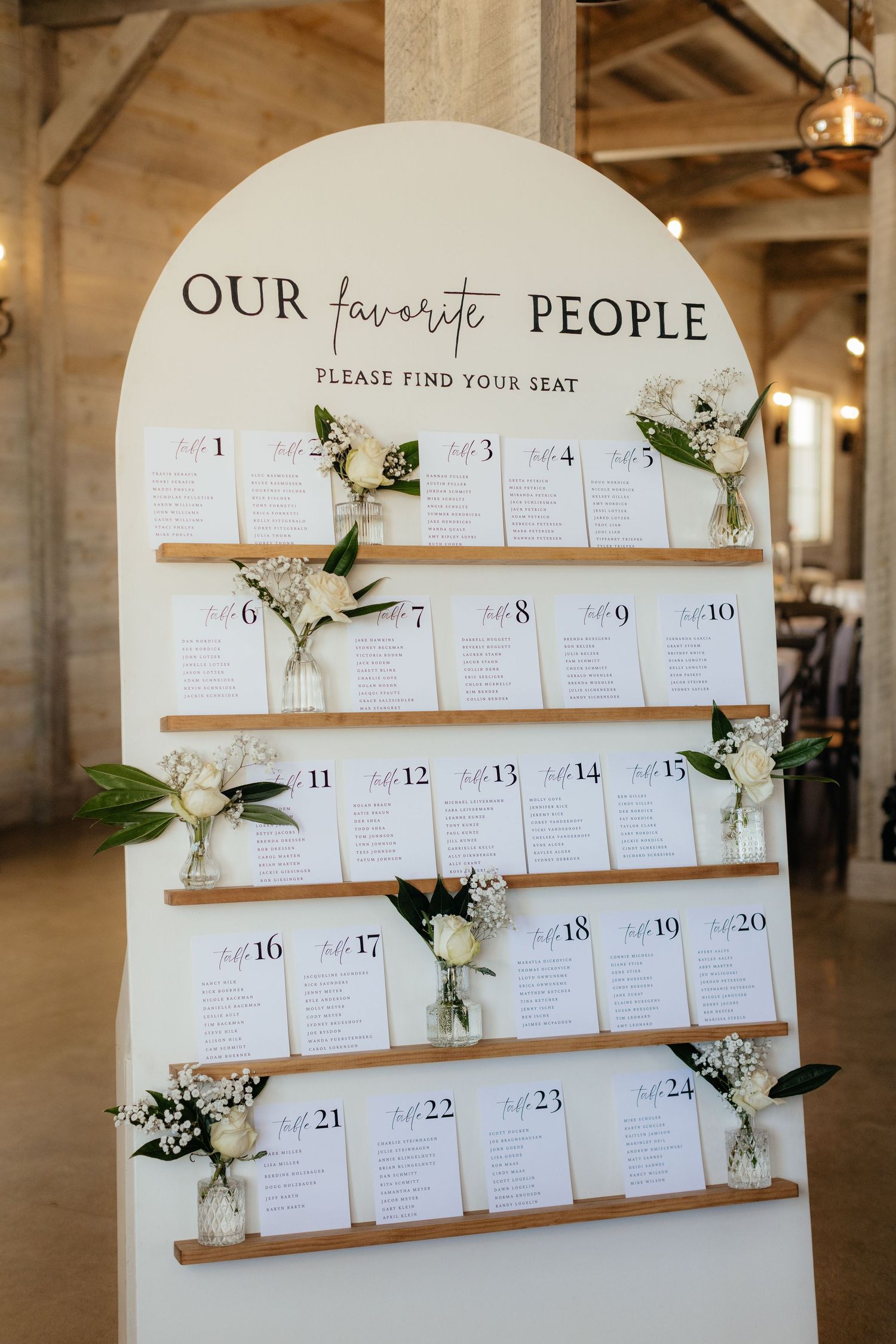 Elegant wedding seating chart display with fresh floral accents and wooden slats.