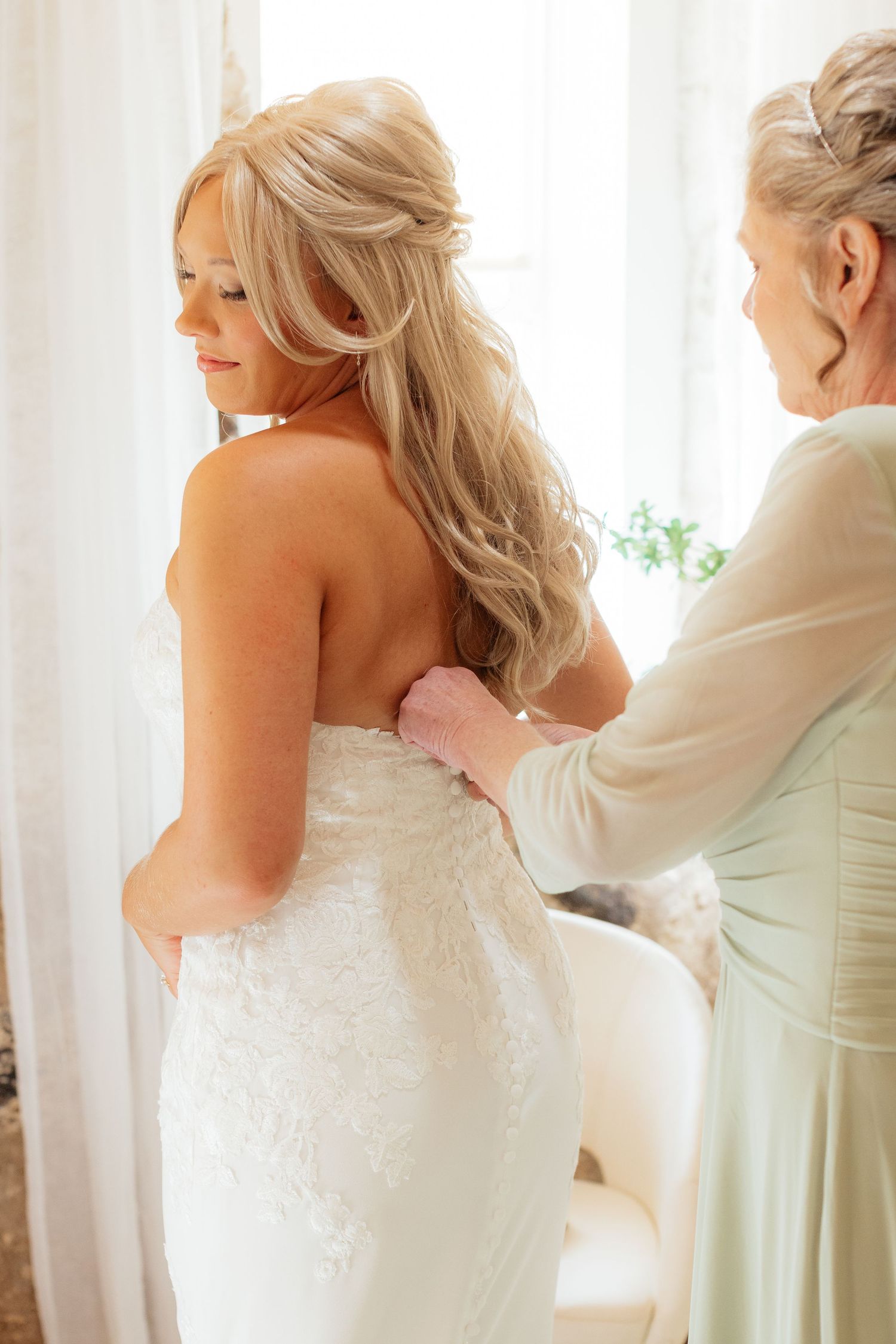 Close up of a white wedding dress being laced up from behind.