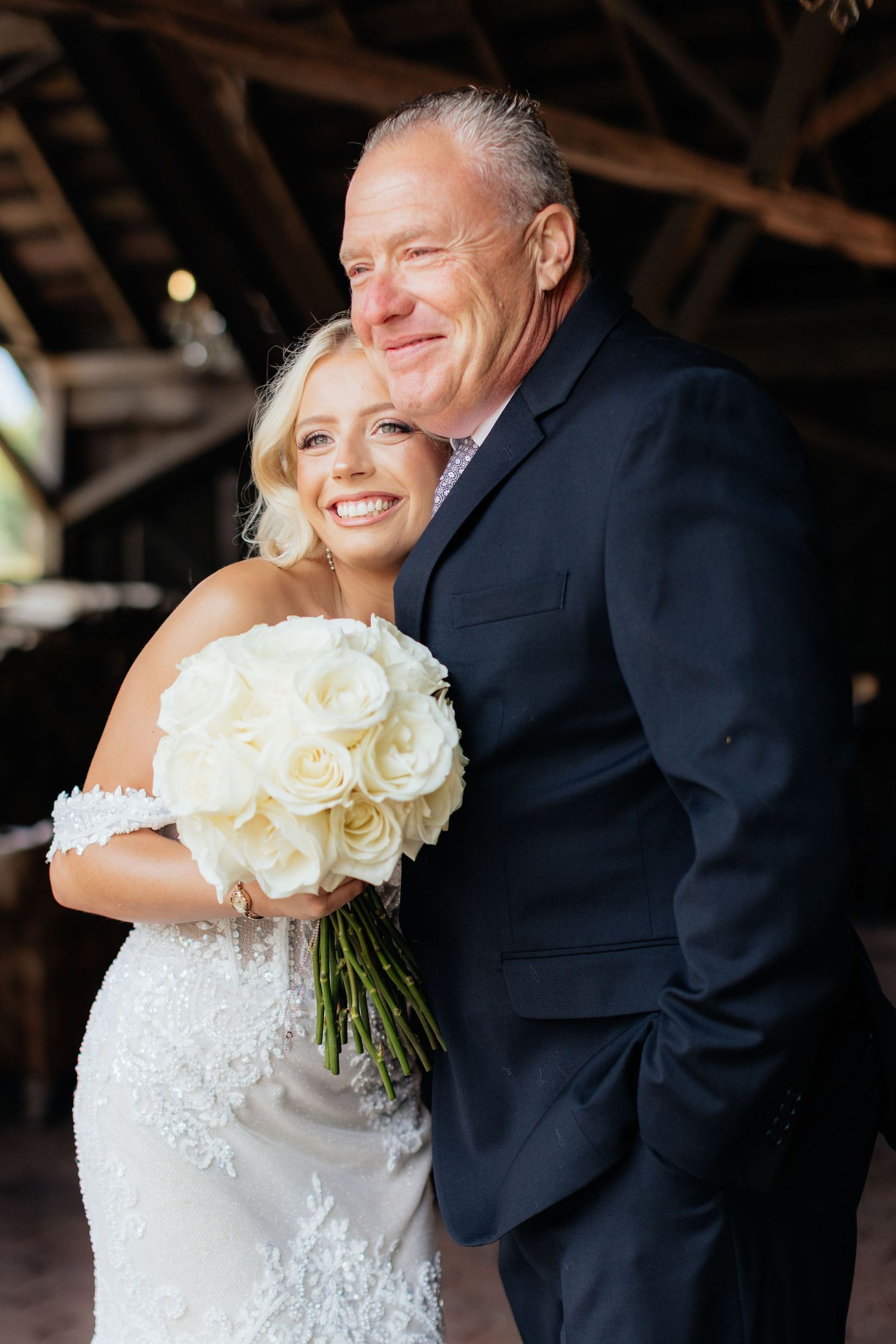 Romantic wedding moment captured with white rose bouquet and joyful laughter.