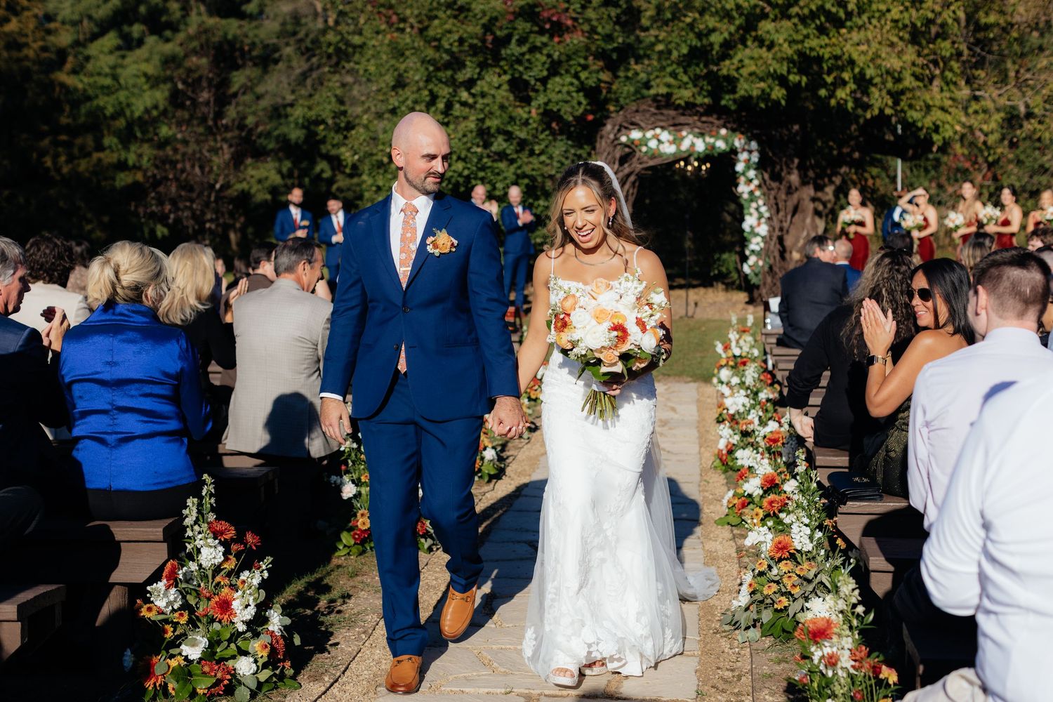 Outdoor wedding ceremony with floral arch and guests in attendance.