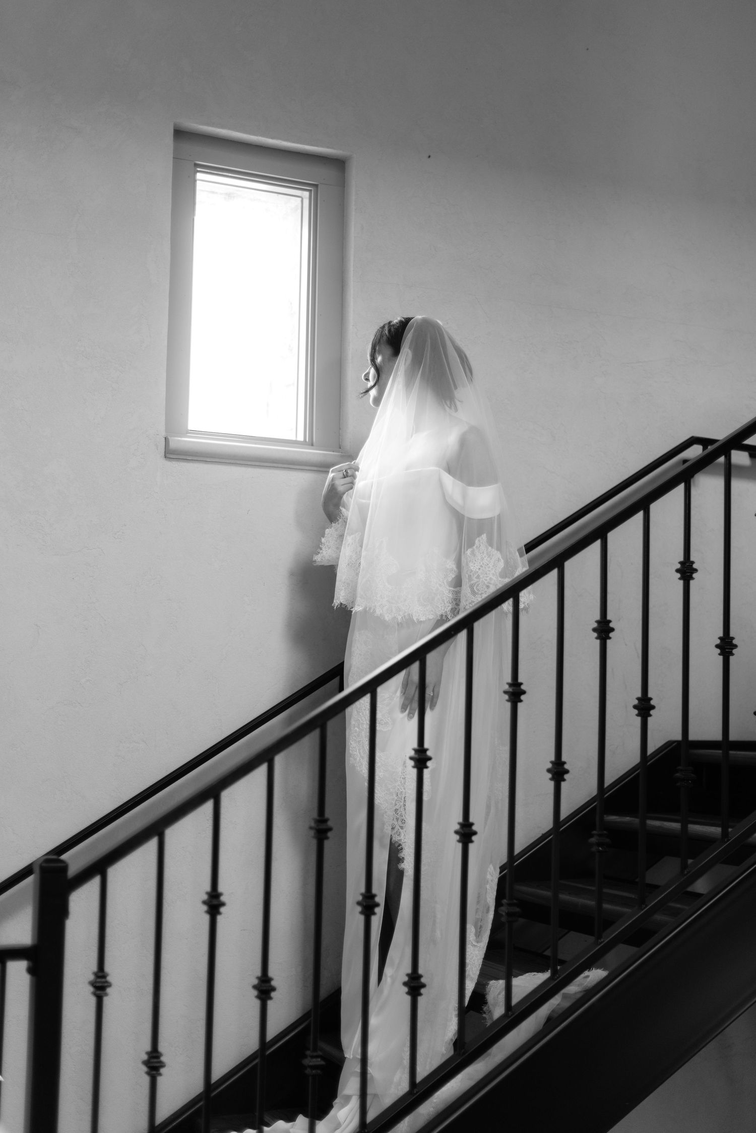 Black and white series showing a bride ascending stairs in a flowing wedding dress.
