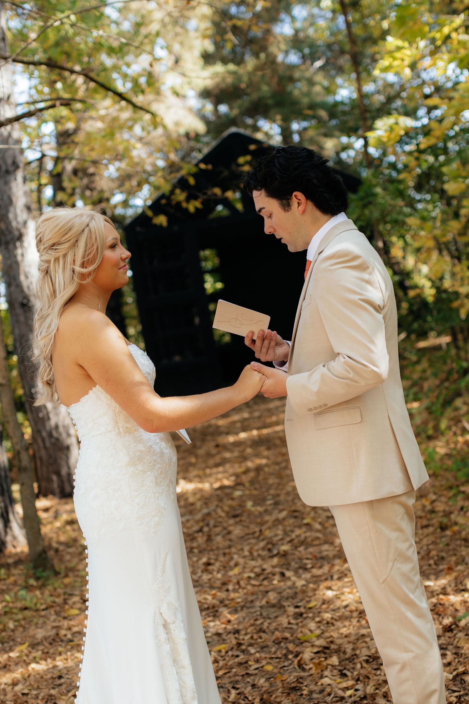 Couple exchanging personal vows during outdoor autumn wedding ceremony.
