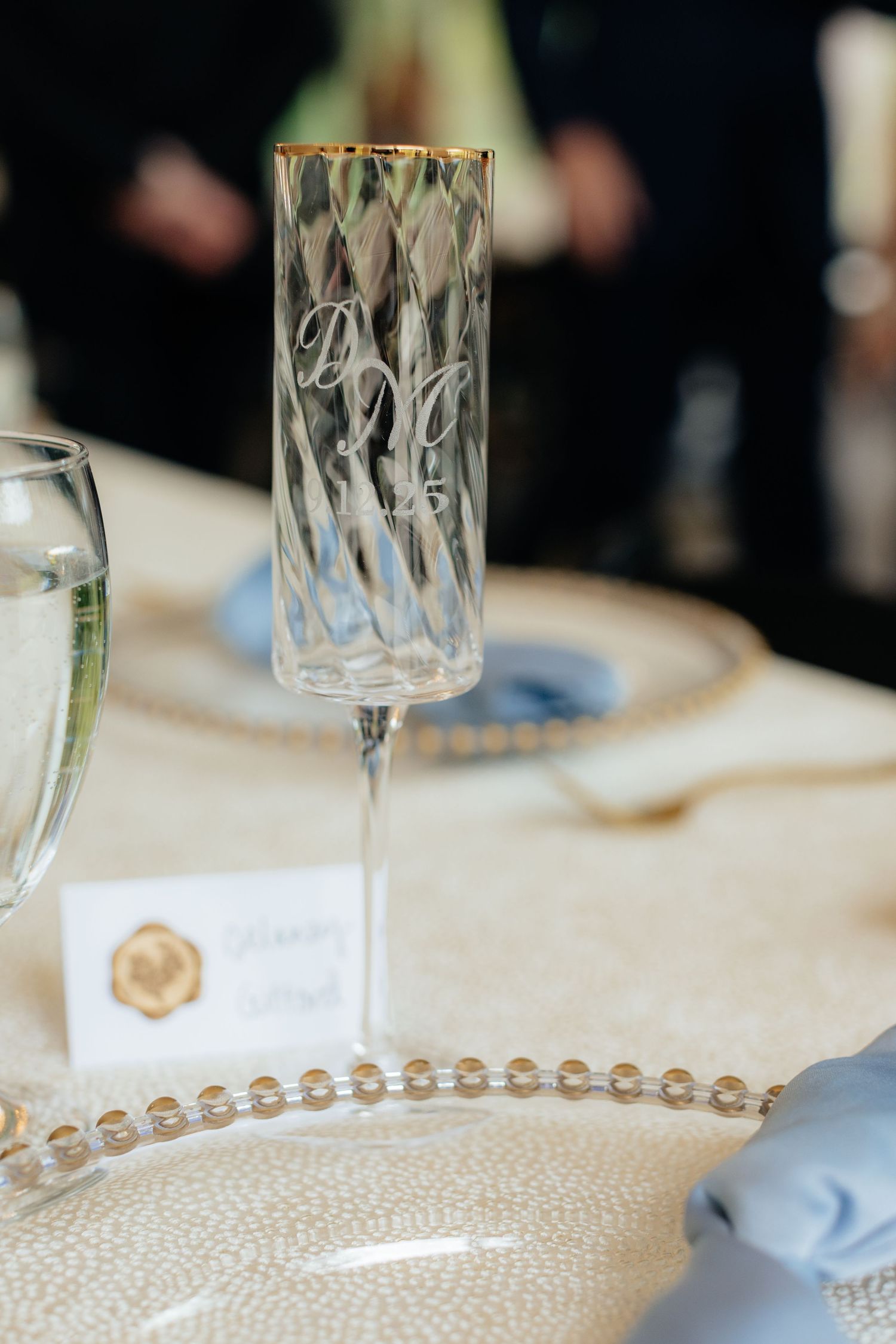 Elegant crystal champagne flute and place setting with pearl beaded charger plate at wedding reception.