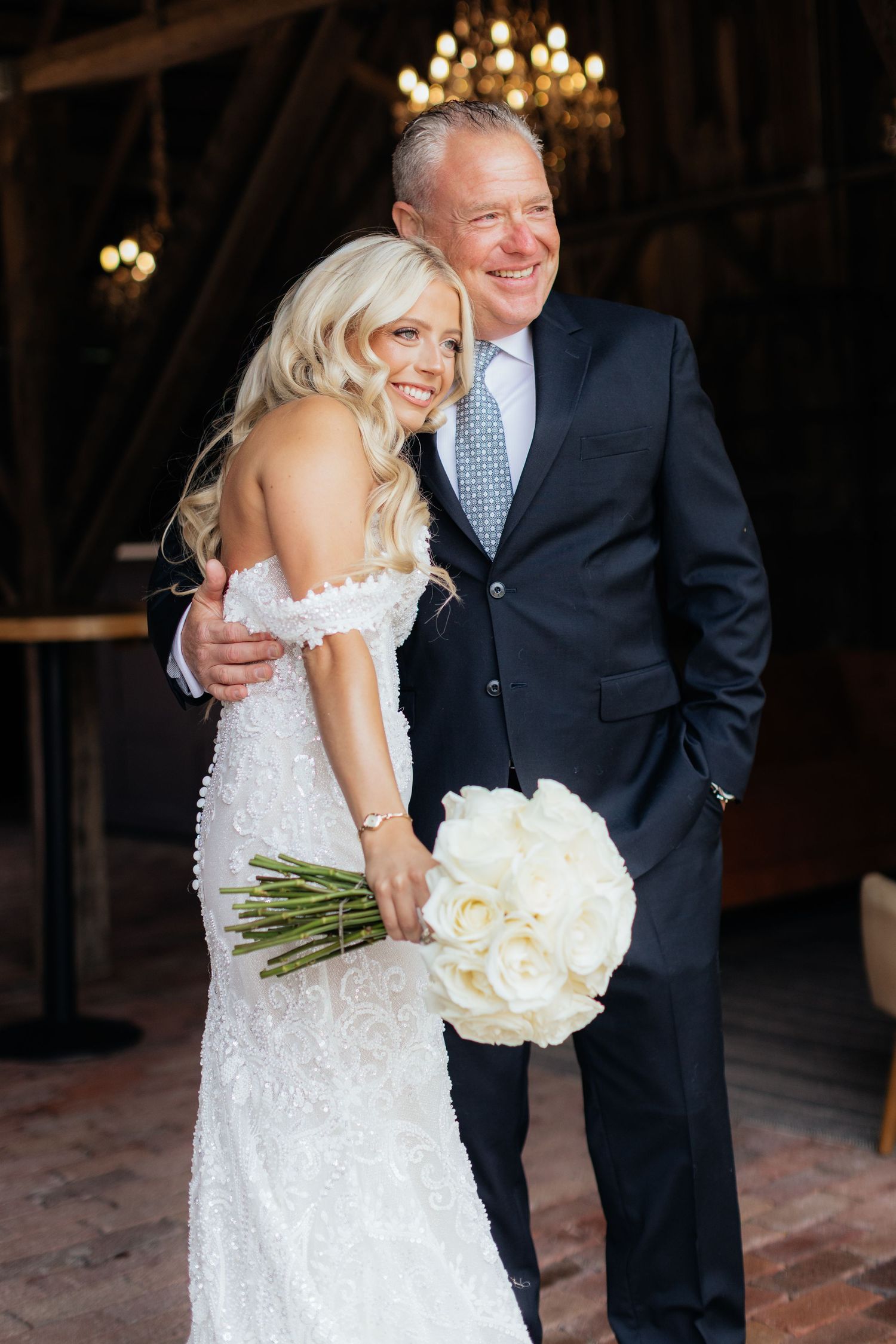 Intimate wedding moment with white roses and elegant lace dress details.