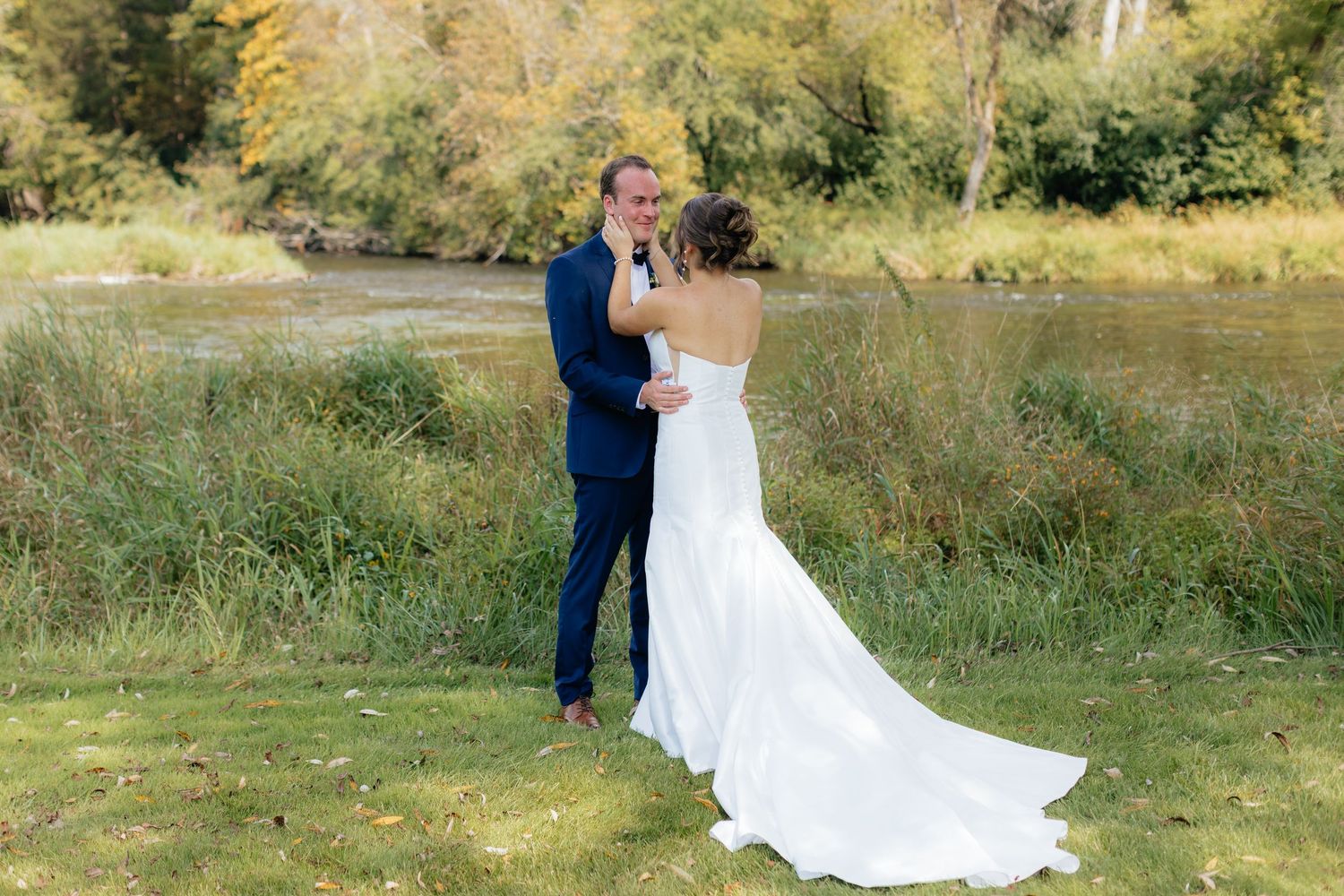 A wedding couple poses for romantic portraits in a sunlit meadow with natural greenery.