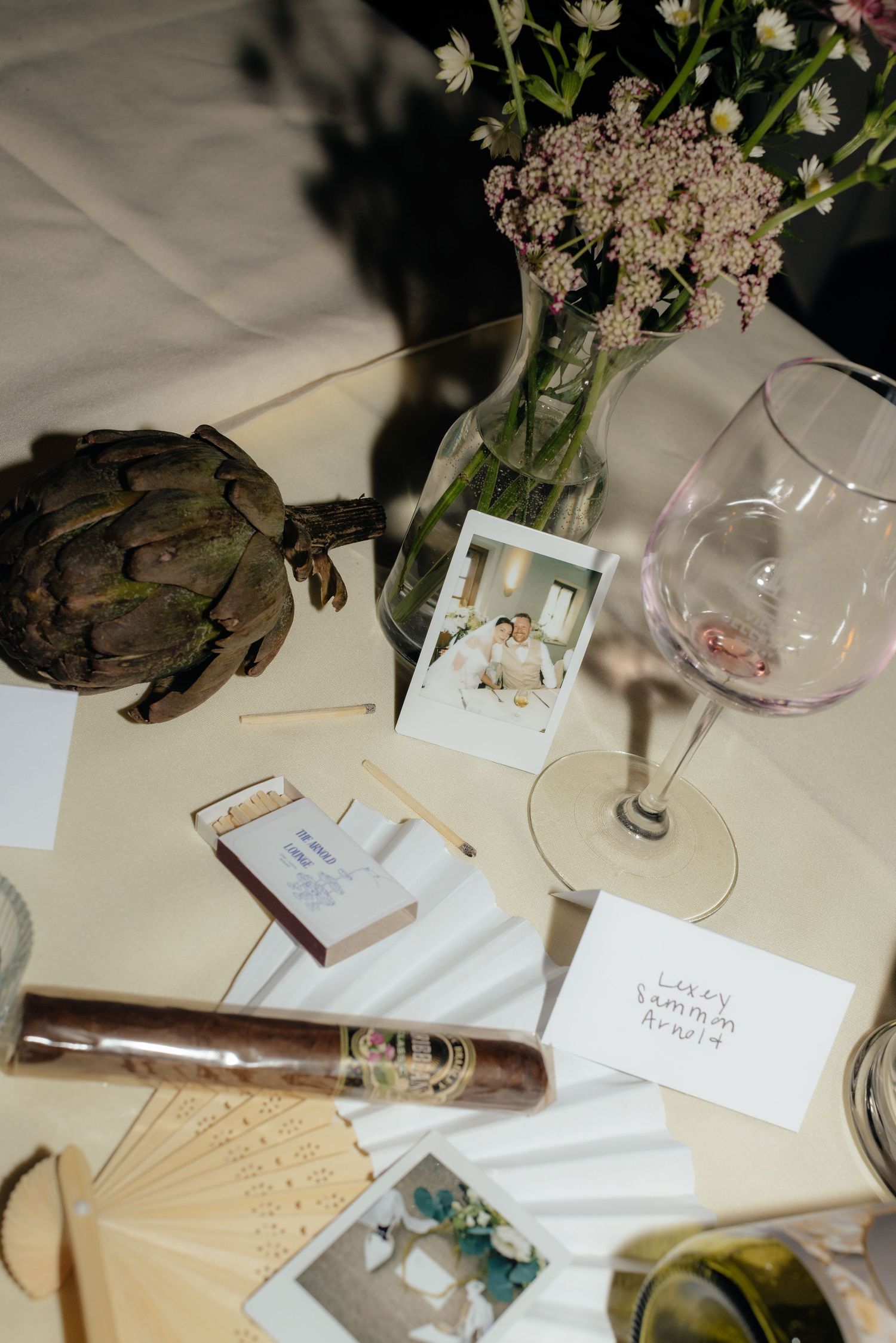 Wedding reception table details with wine glasses, candles and floral arrangements.