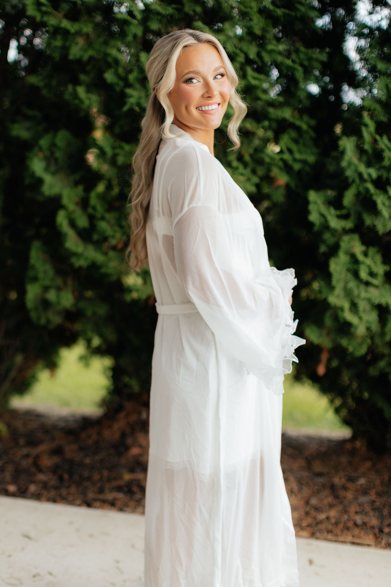 An elegant white flowing robe photographed against green foliage outdoors.
