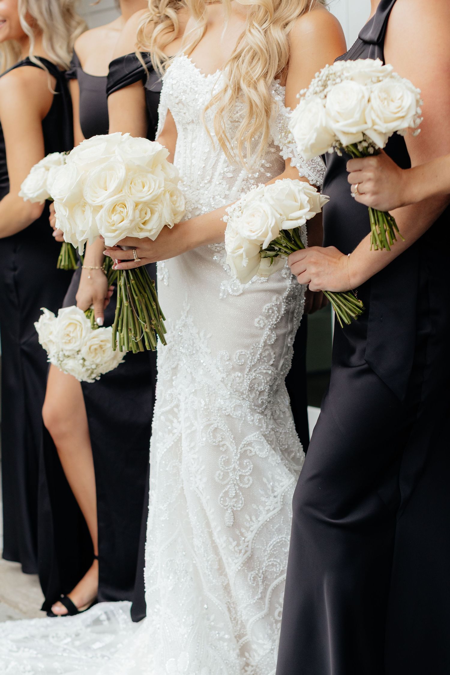 Wedding party detail shot showing contrast of black bridesmaid dresses against white lace bridal gown.
