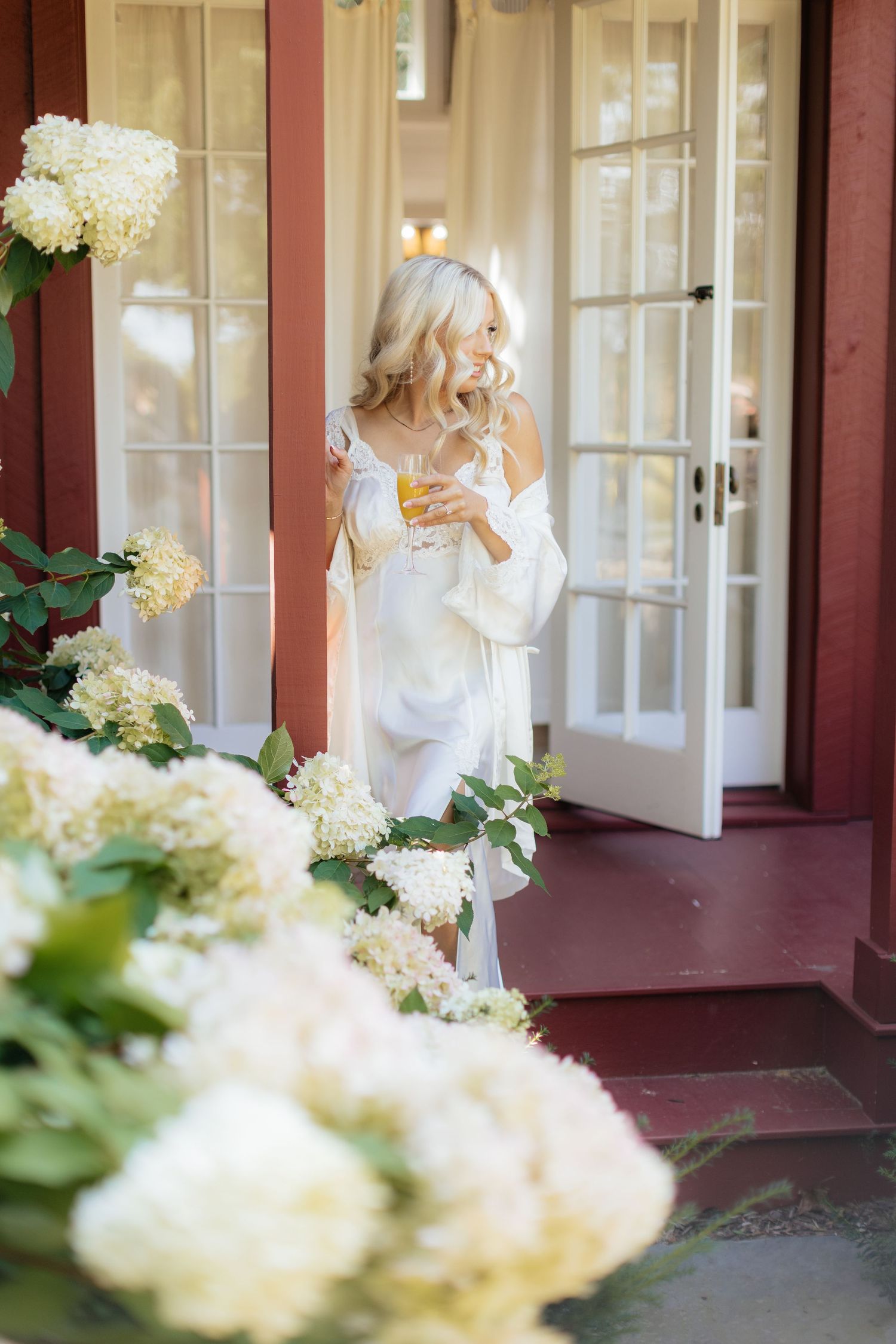 Elegant white hydrangeas frame a porch entrance with French doors.