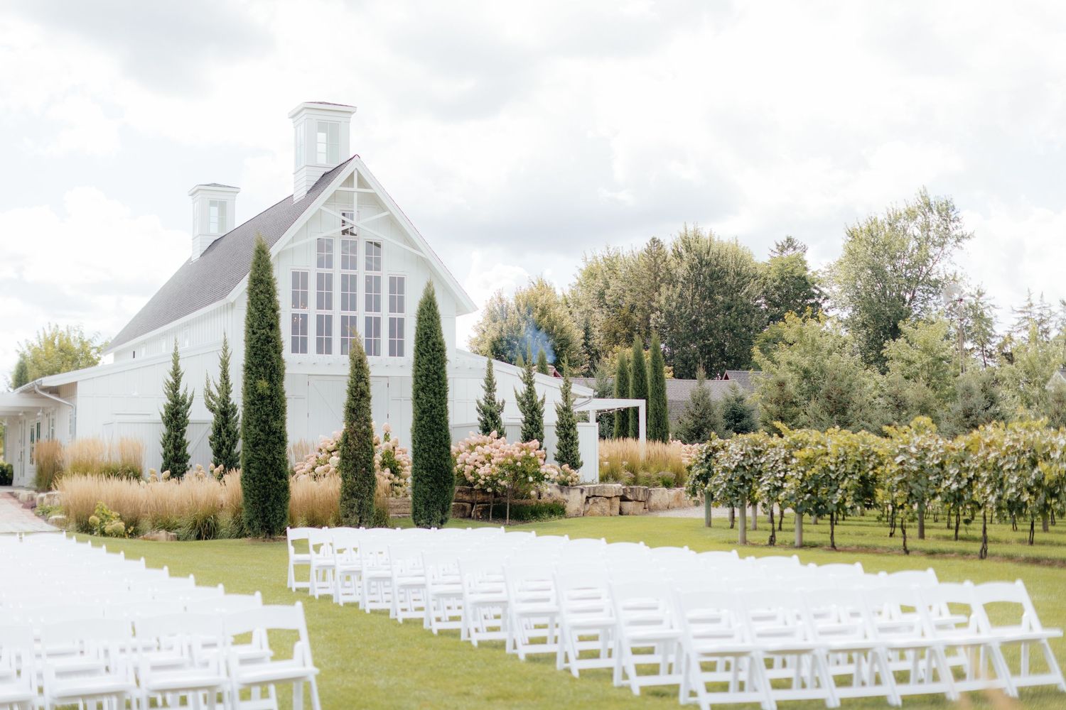 White chapel wedding venue with rows of white chairs set up on a lawn for an outdoor ceremony.