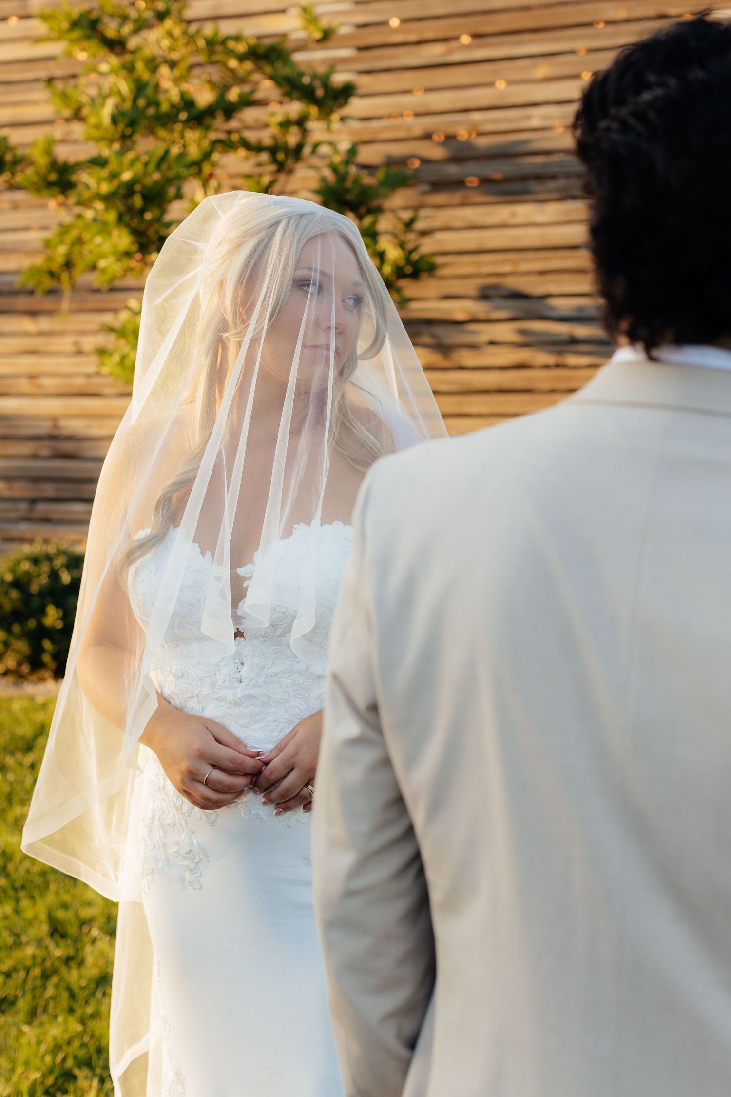 Back view of couple in wedding attire standing together outdoors.