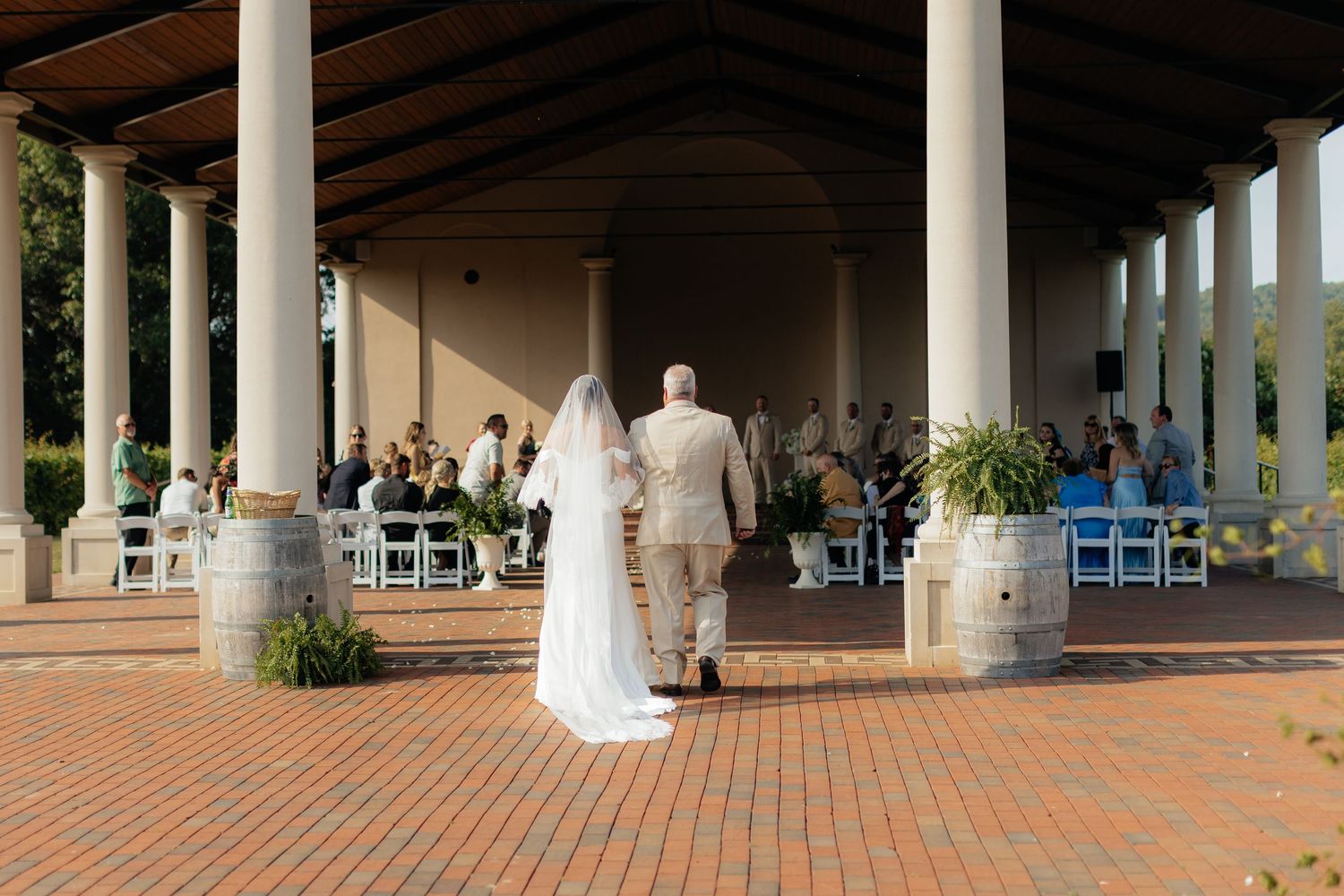 Wedding venue exterior features elegant columns and brick patio with seating setup.