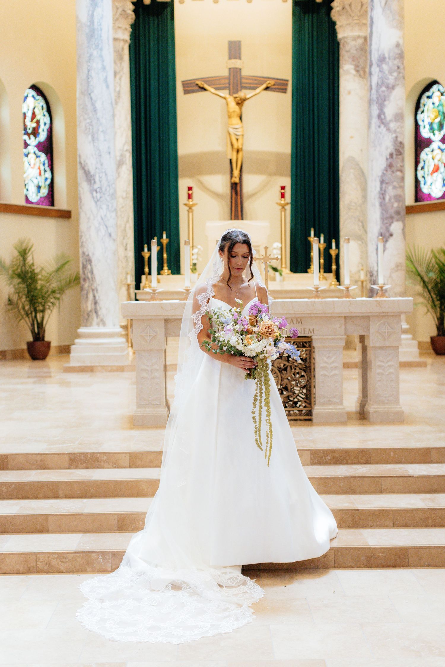 Wedding dress displayed in a church sanctuary with marble columns and green curtains.