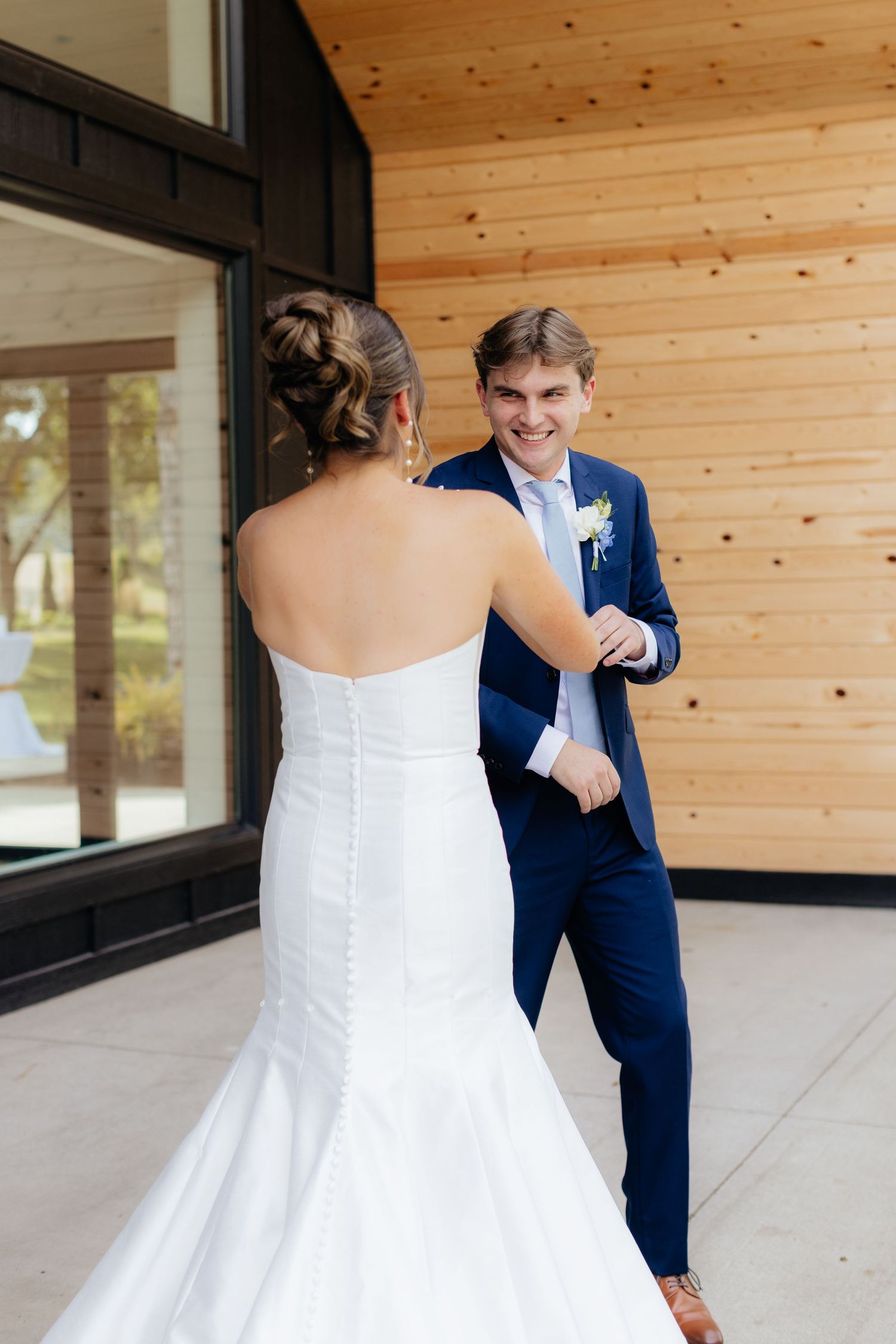 A couple shares their first look moment outside a modern wooden venue.