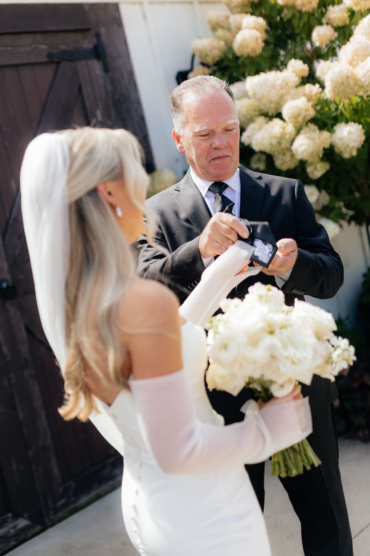Emotional first look between bride and father with white floral arrangements.
