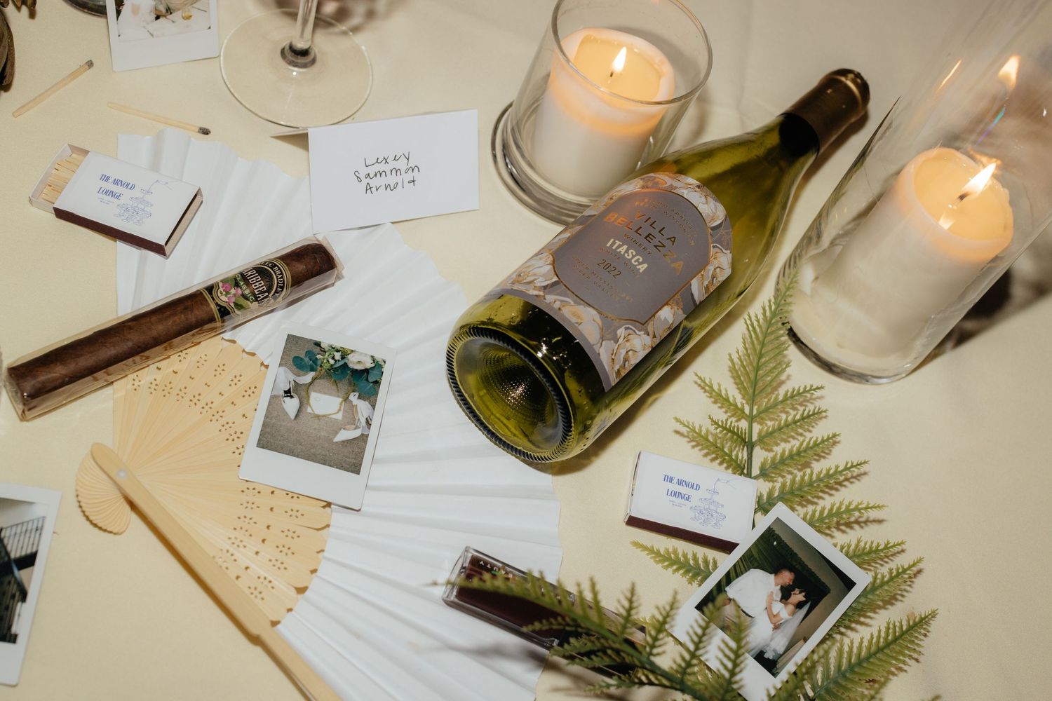 Wedding reception table decorated with lit candles, ferns and vintage details.