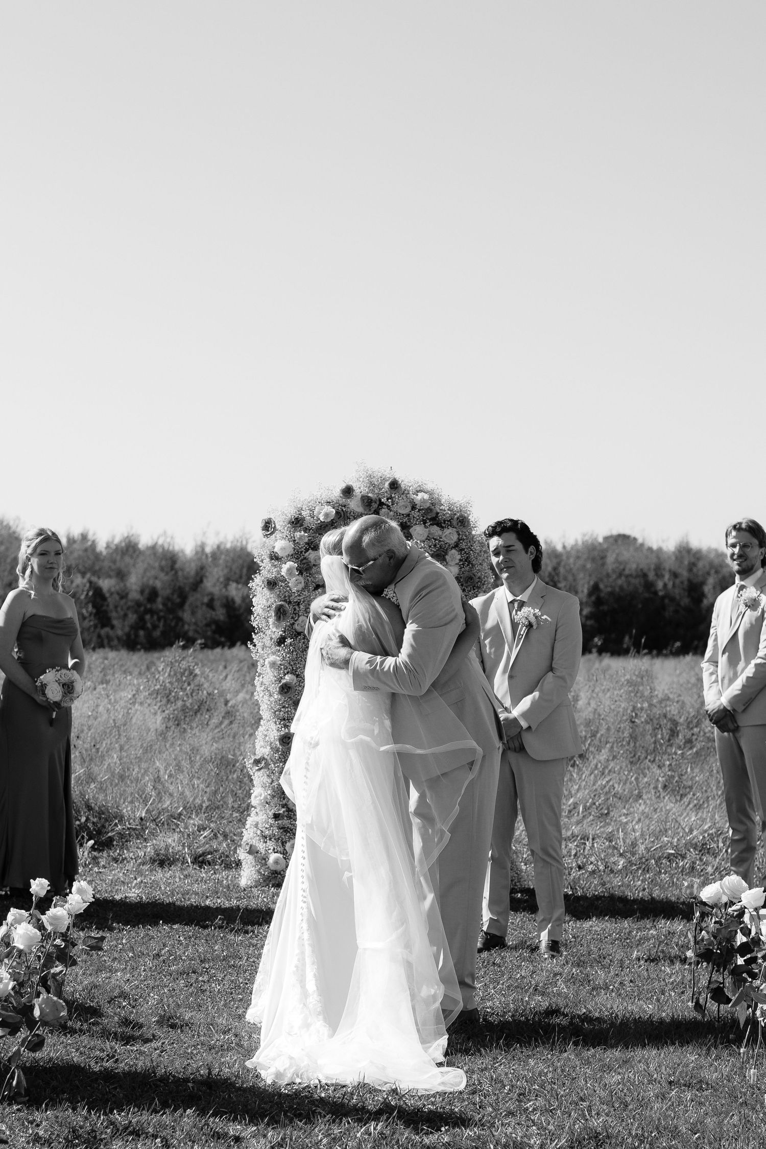 Black and white photo sequence of a wedding couple dancing in a field with guests looking on.