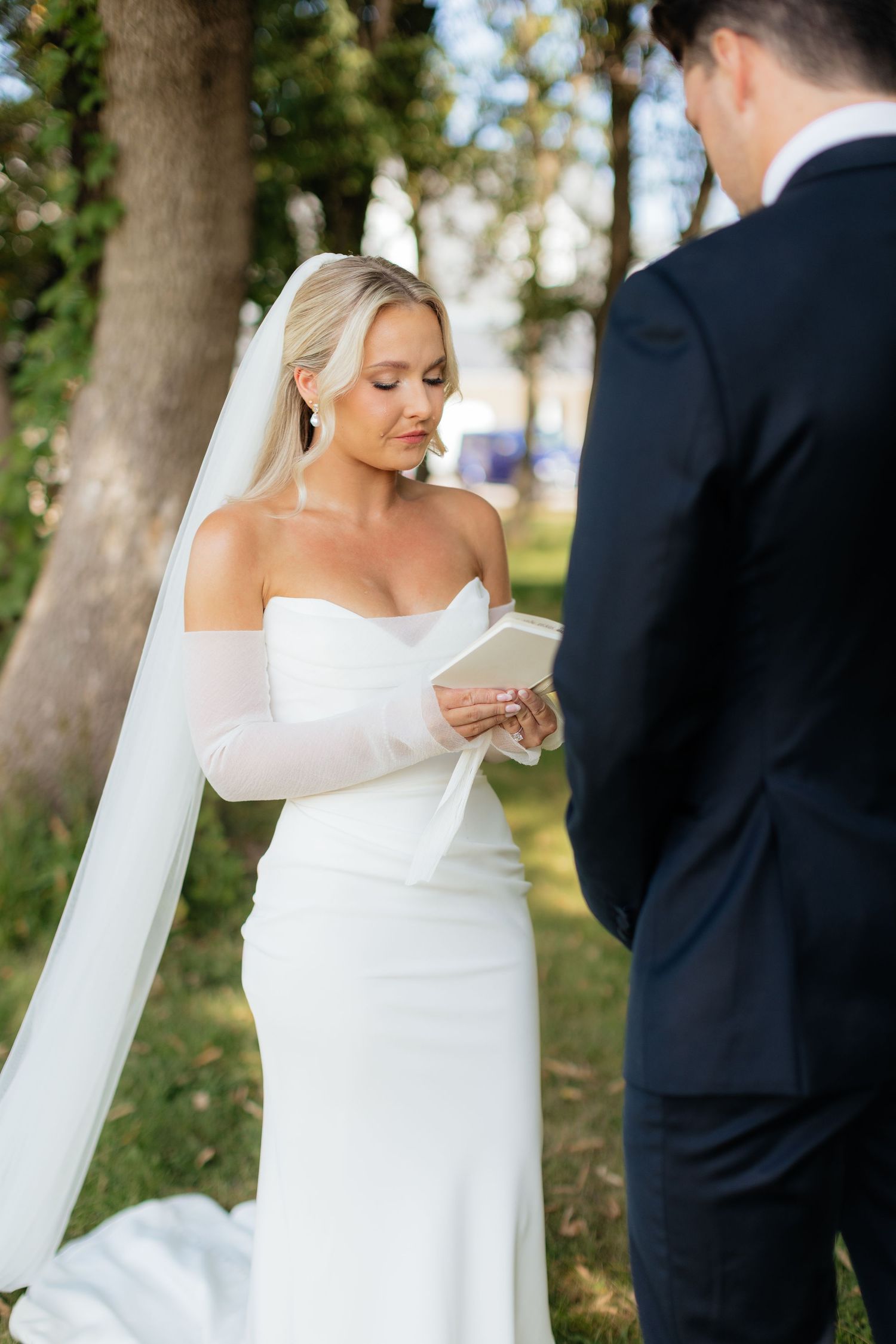 A couple shares an intimate moment during their outdoor wedding photoshoot among trees.