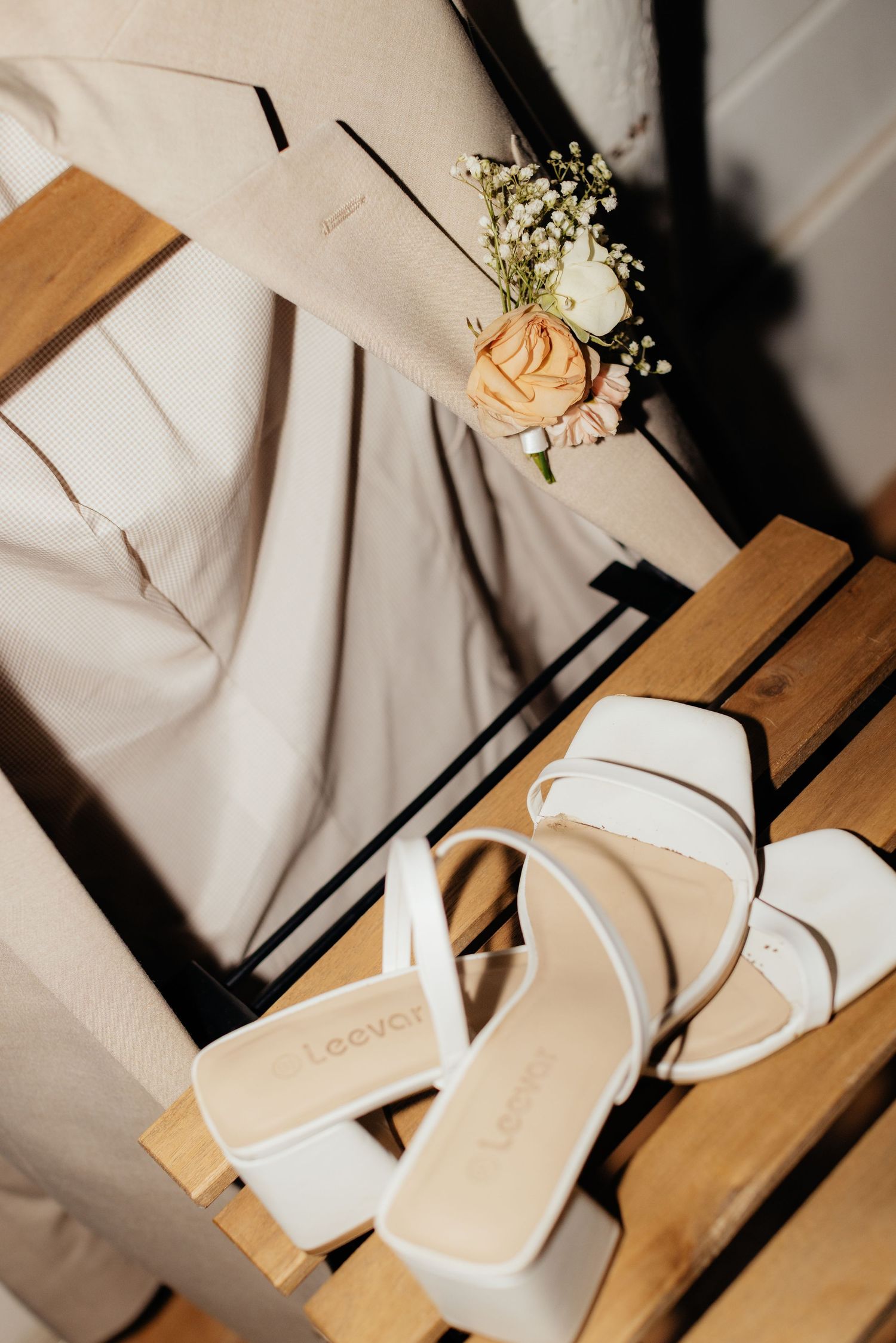 Wedding accessories including beige shoes and delicate floral boutonniere.
